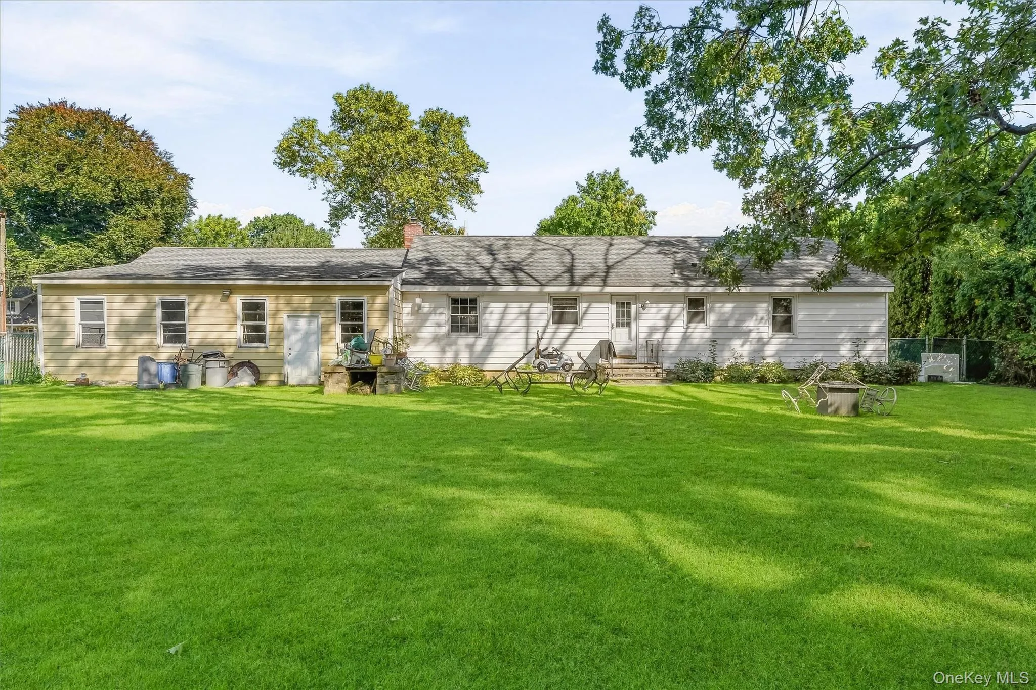 Expansive backyard featuring a manicured lawn, established trees, and two single-story structures with siding Expansive backyard featuring a manicured lawn, established trees, and two single-story structures with siding