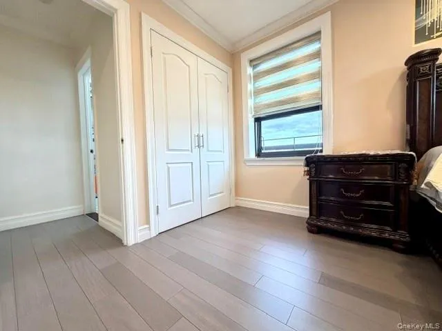 Wood-finish flooring, white paneled double doors, window with horizontal blinds, and crown molding Wood-finish flooring, white paneled double doors, window with horizontal blinds, and crown molding