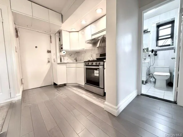 Compact kitchen featuring white cabinetry, stainless steel oven, and undermount sink with a wall-mounted faucet Compact kitchen featuring white cabinetry, stainless steel oven, and undermount sink with a wall-mounted faucet