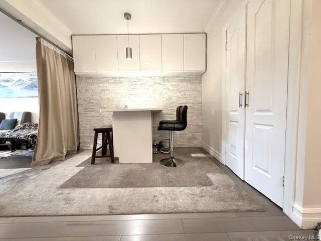 White built-in cabinetry over a textured stone-look accent wall, wood-finish flooring, and white paneled doors White built-in cabinetry over a textured stone-look accent wall, wood-finish flooring, and white paneled doors