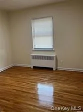 Unfurnished room featuring dark hardwood / wood-style flooring and radiator heating unit Unfurnished room featuring dark hardwood / wood-style flooring and radiator heating unit