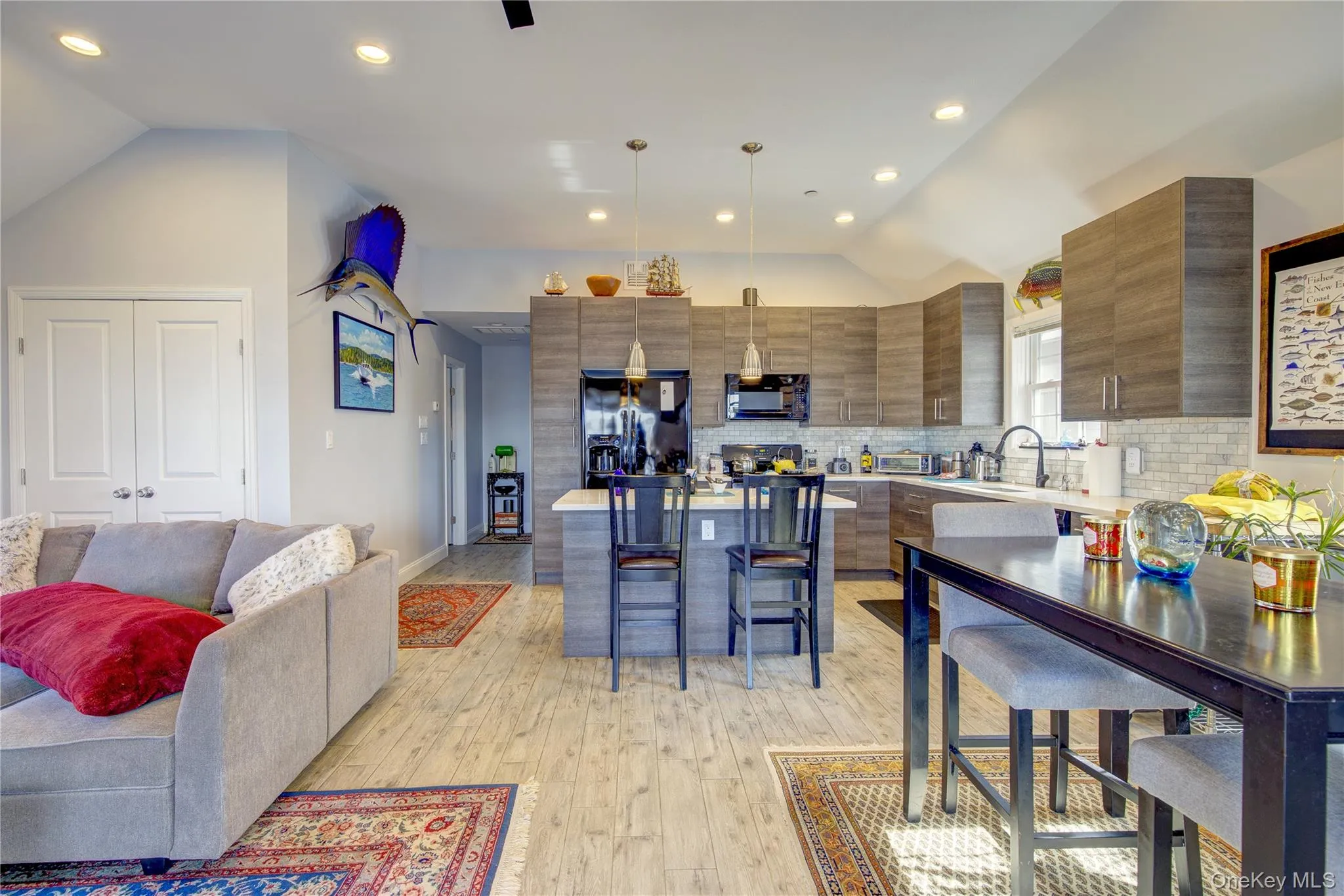 Kitchen with lofted ceiling, backsplash, black appliances, recessed lighting, and a kitchen bar Kitchen with lofted ceiling, backsplash, black appliances, recessed lighting, and a kitchen bar