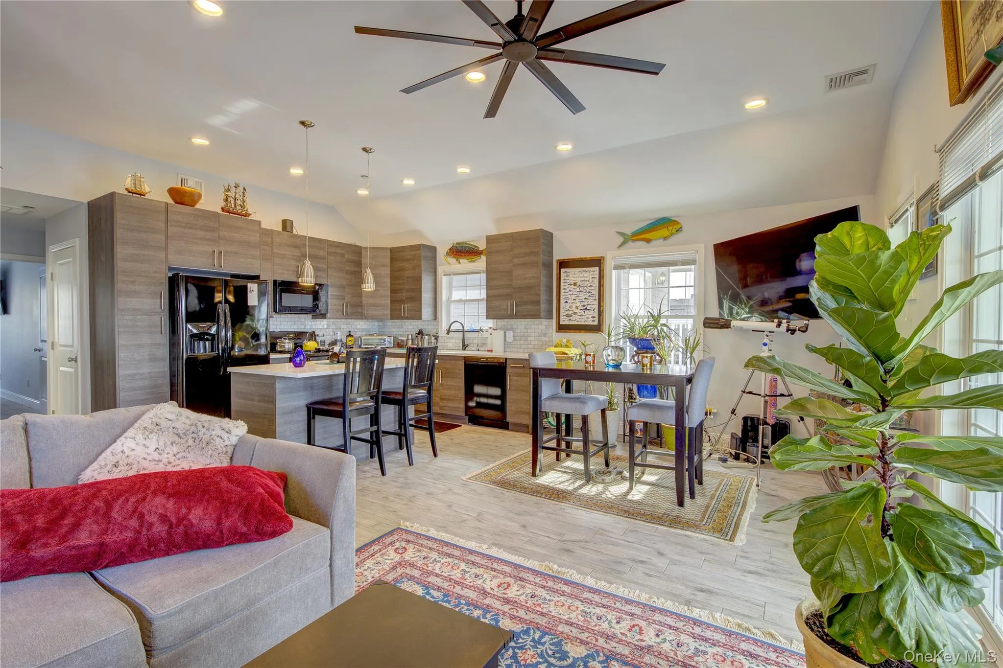 Living room featuring recessed lighting, vaulted ceiling, light wood-style flooring, and a ceiling fan Living room featuring recessed lighting, vaulted ceiling, light wood-style flooring, and a ceiling fan
