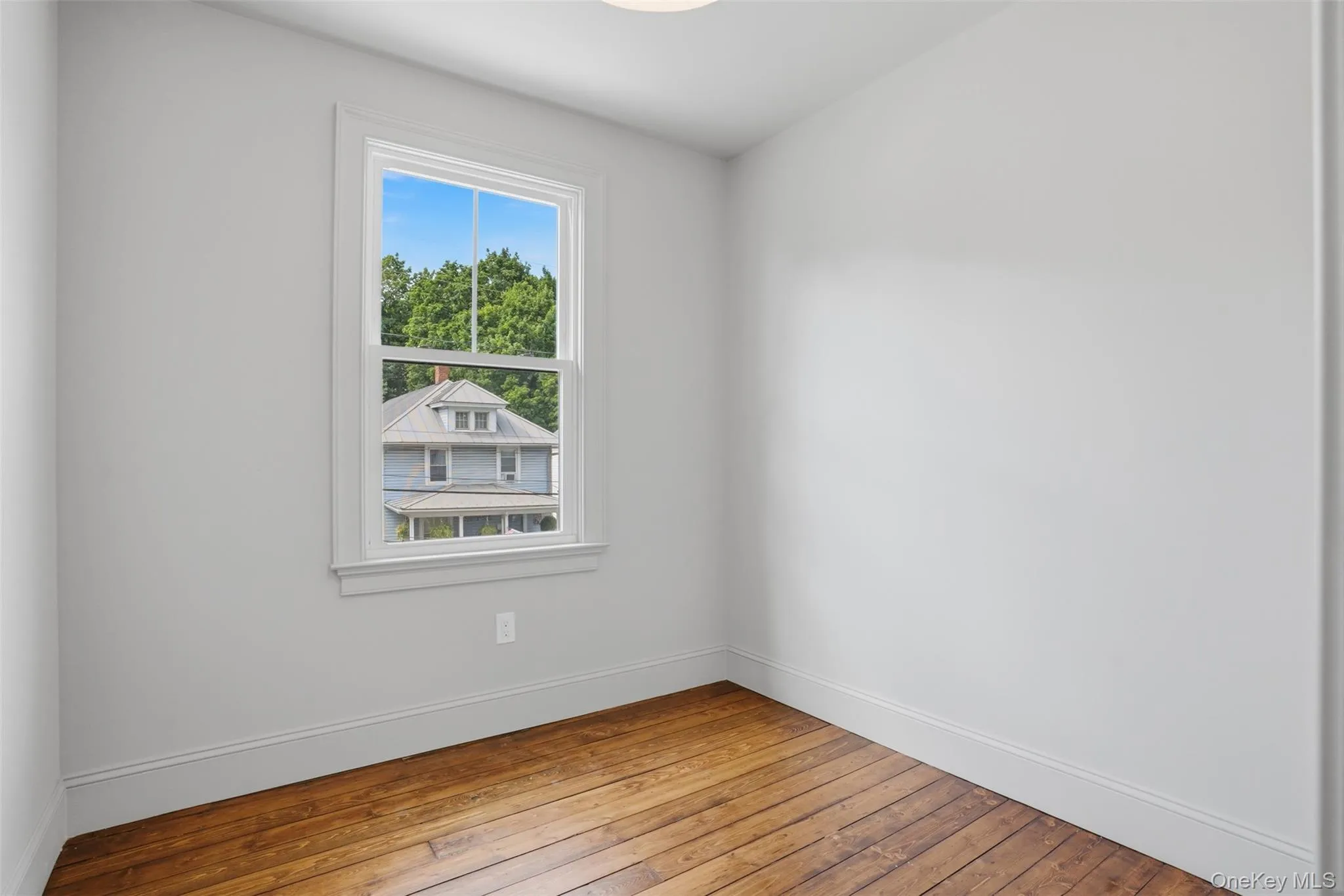 Hardwood flooring, painted walls, window with white trim, and a ceiling-mounted light fixture Hardwood flooring, painted walls, window with white trim, and a ceiling-mounted light fixture