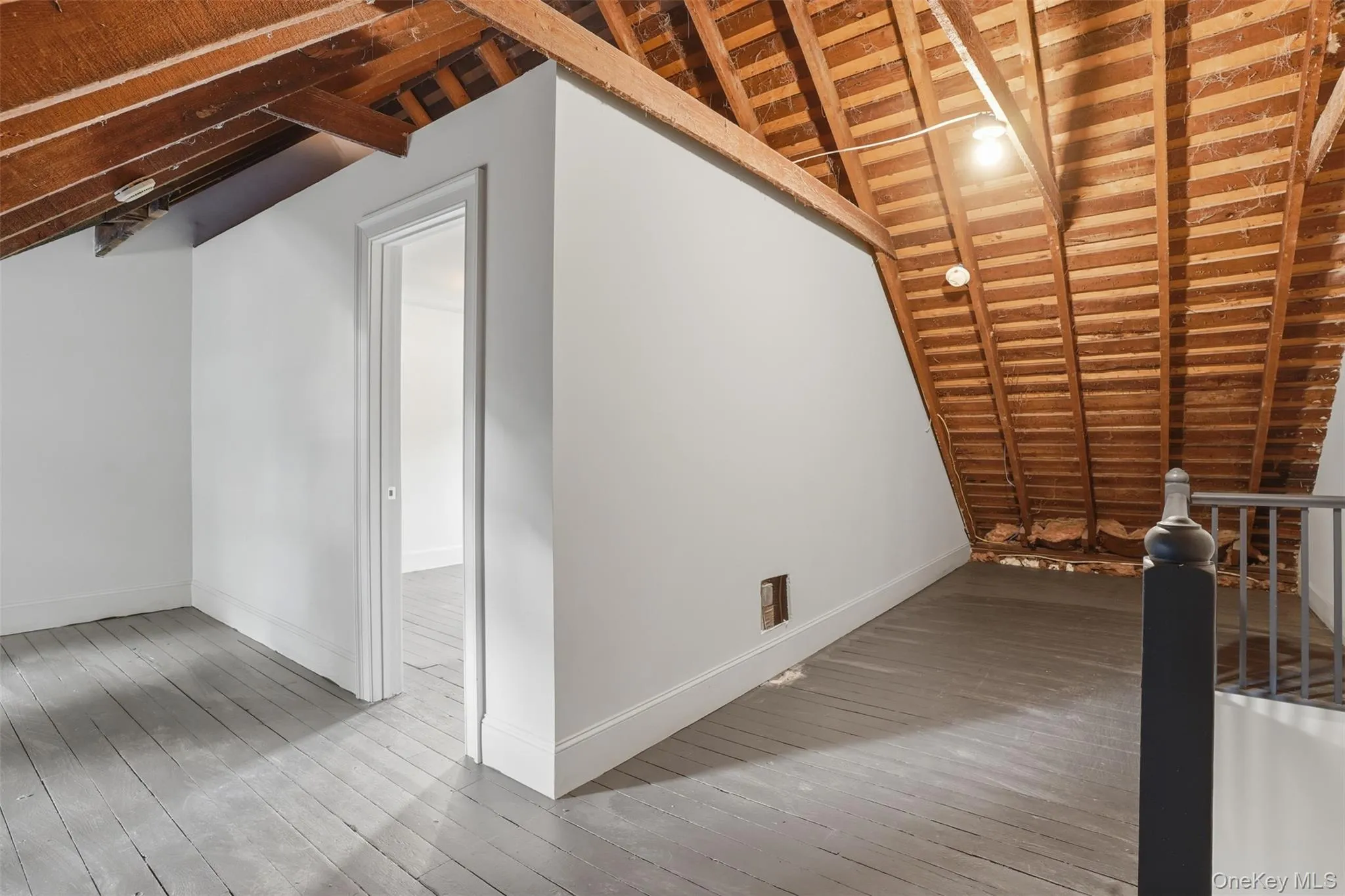 Exposed wood rafter ceiling, painted wood flooring, white painted walls, and an interior doorway Exposed wood rafter ceiling, painted wood flooring, white painted walls, and an interior doorway