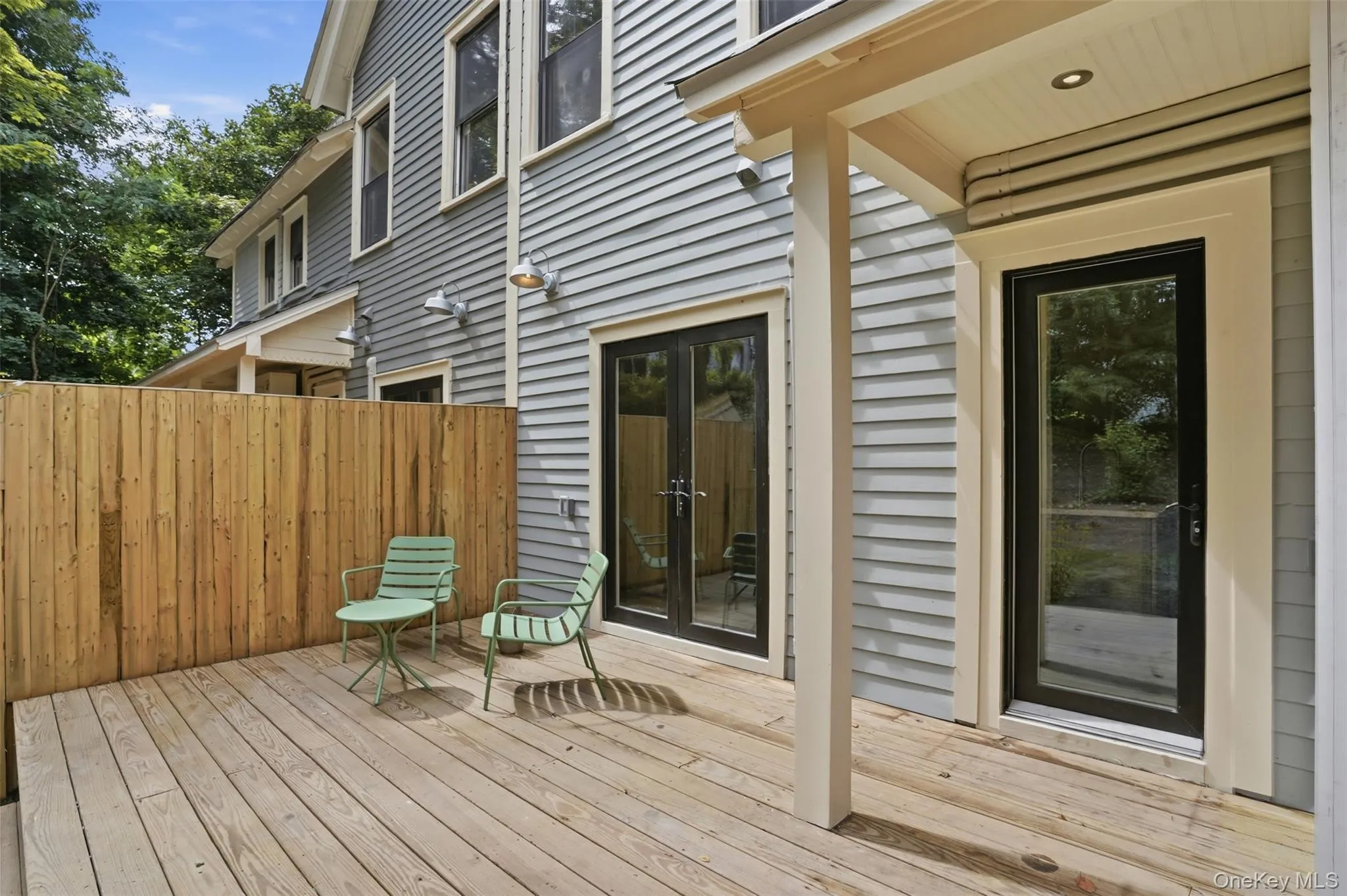 Expansive wood deck with a privacy fence, two exterior doors, and a covered porch area Expansive wood deck with a privacy fence, two exterior doors, and a covered porch area