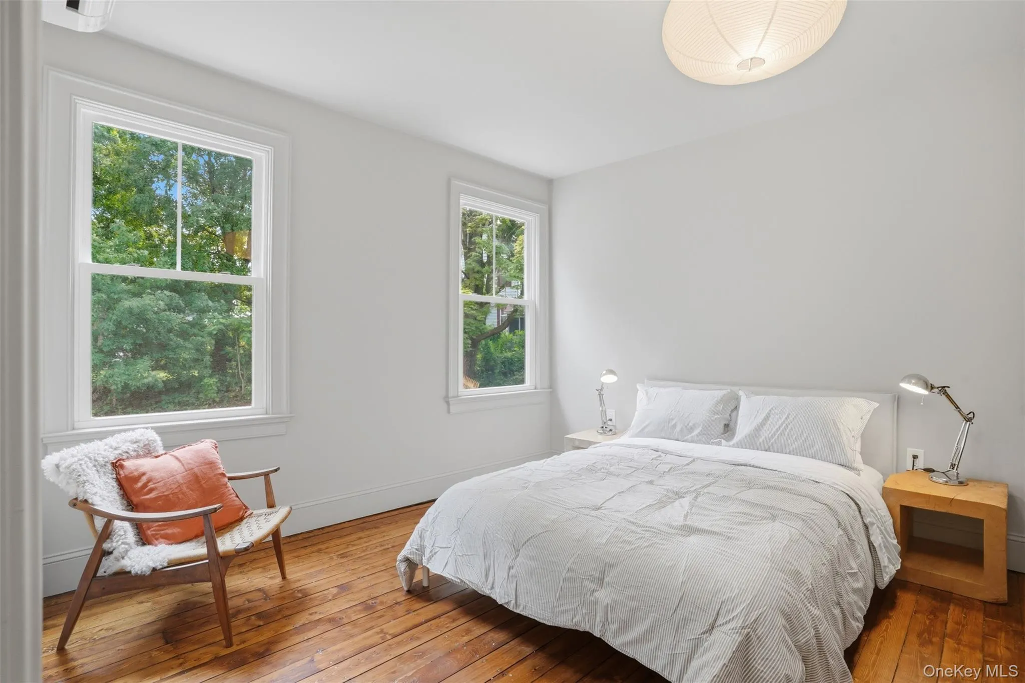Hardwood flooring, white walls, two single-hung windows, and a flush mount ceiling light fixture Hardwood flooring, white walls, two single-hung windows, and a flush mount ceiling light fixture