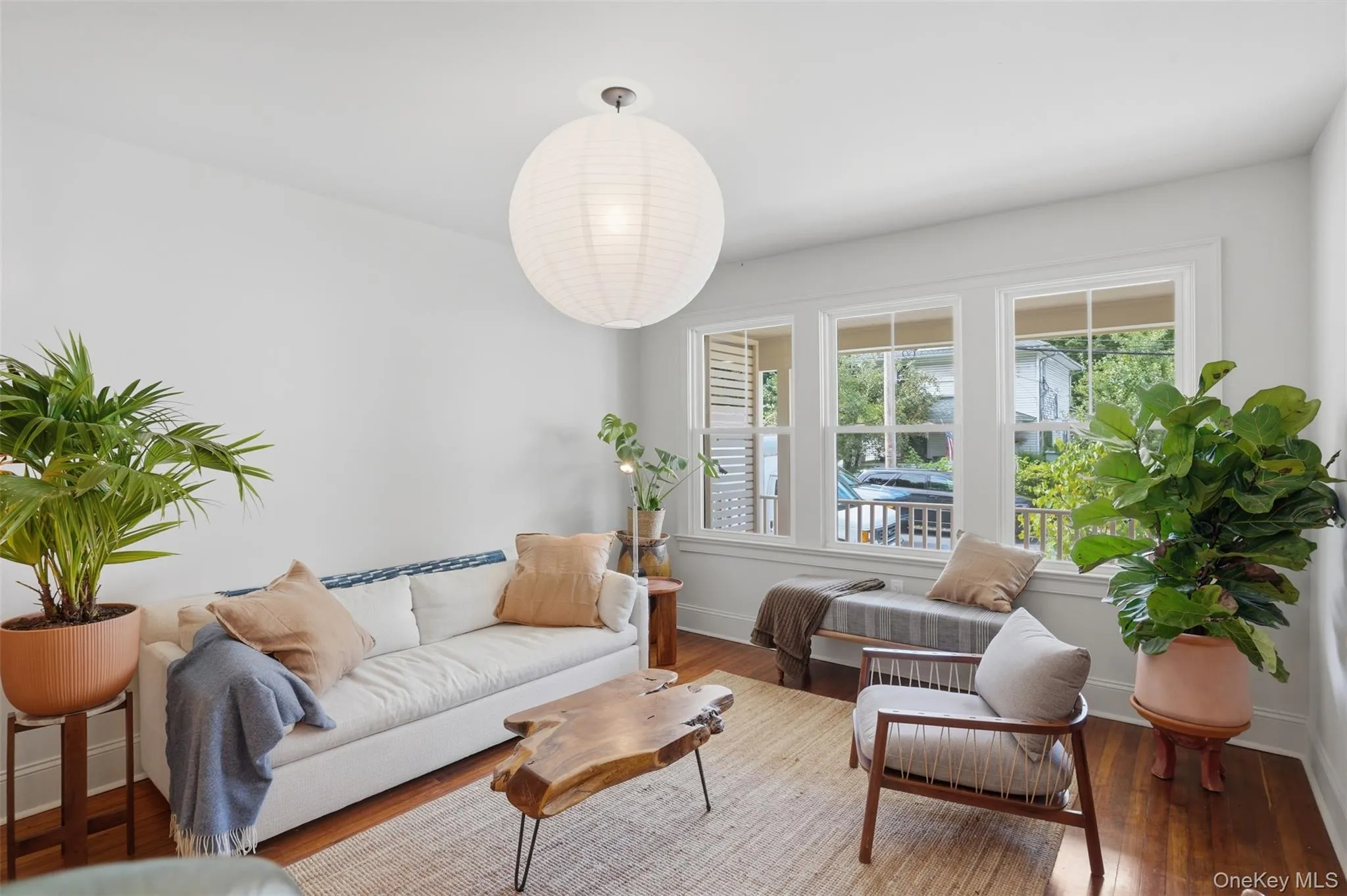 Hardwood flooring, white walls, triple window unit, white trim, and a contemporary ceiling fixture Hardwood flooring, white walls, triple window unit, white trim, and a contemporary ceiling fixture