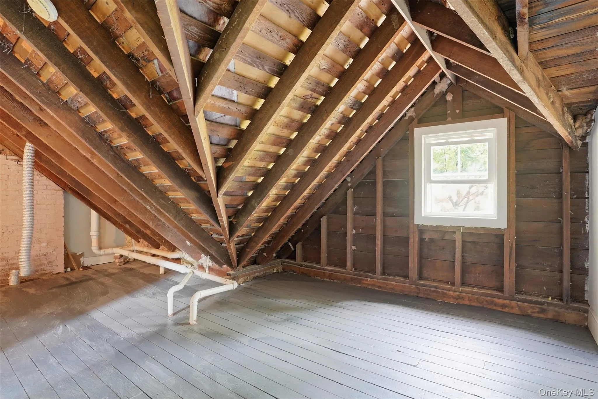Exposed wood rafters, painted wood flooring, and a white-framed window Exposed wood rafters, painted wood flooring, and a white-framed window