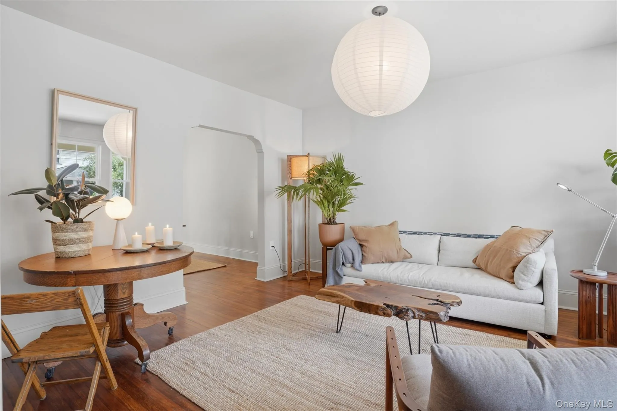 Hardwood flooring, arched doorway, recessed wall mirror, white ceiling, and a large circular pendant light fixture Hardwood flooring, arched doorway, recessed wall mirror, white ceiling, and a large circular pendant light fixture