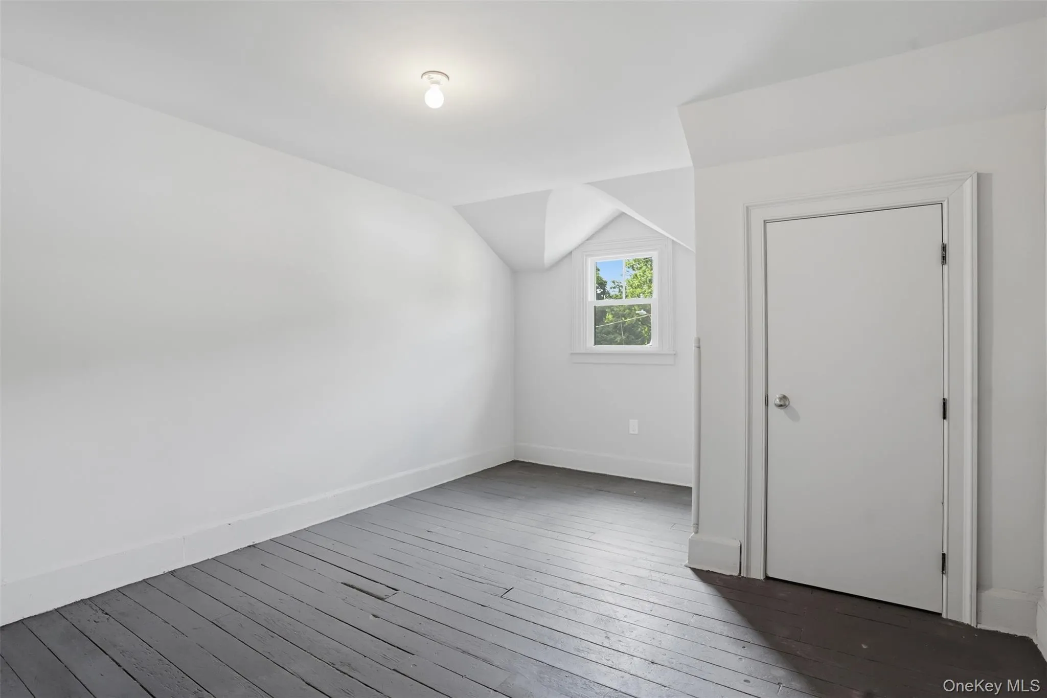 Painted wood flooring, white walls, angled ceiling, single window, interior door Painted wood flooring, white walls, angled ceiling, single window, interior door