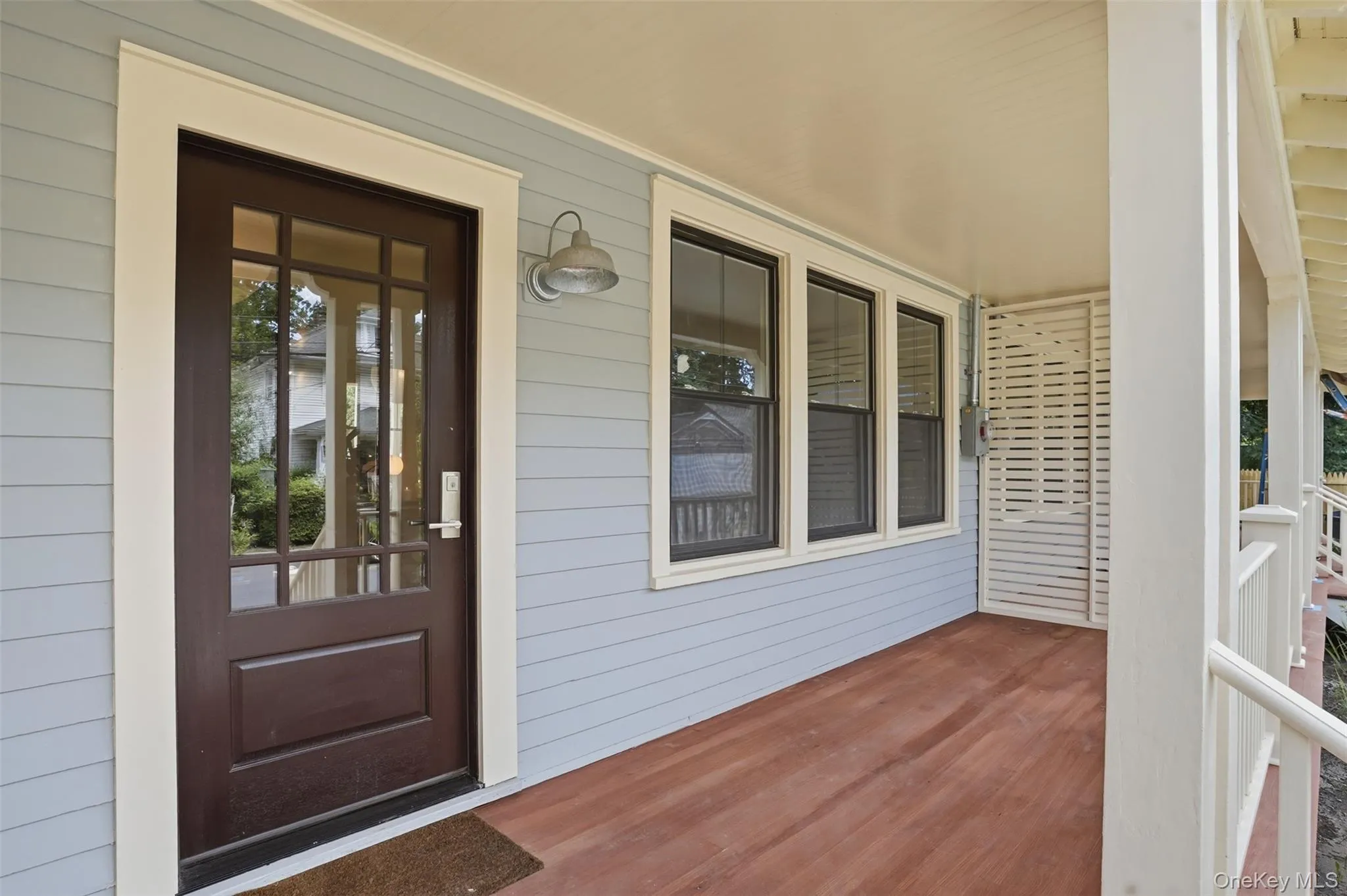 Covered porch with wood-finish flooring, light blue siding, and white trim accents Covered porch with wood-finish flooring, light blue siding, and white trim accents