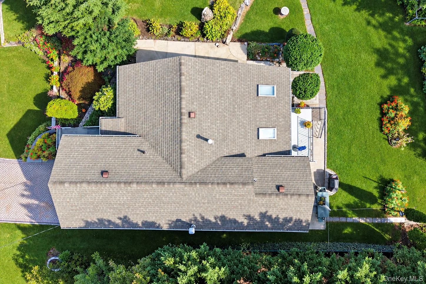 Shingle roof, multiple skylights, paver driveway, manicured lawn, and landscaped garden beds Shingle roof, multiple skylights, paver driveway, manicured lawn, and landscaped garden beds