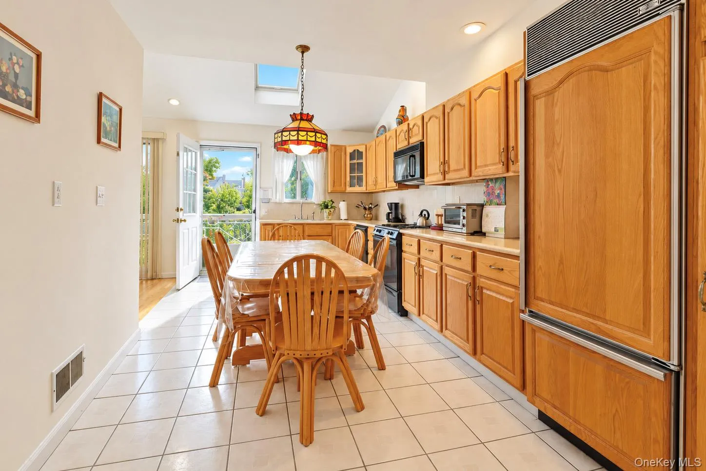 Kitchen featuring light wood-finish cabinetry, light-toned tile flooring, and integrated panel-front refrigerator Kitchen featuring light wood-finish cabinetry, light-toned tile flooring, and integrated panel-front refrigerator