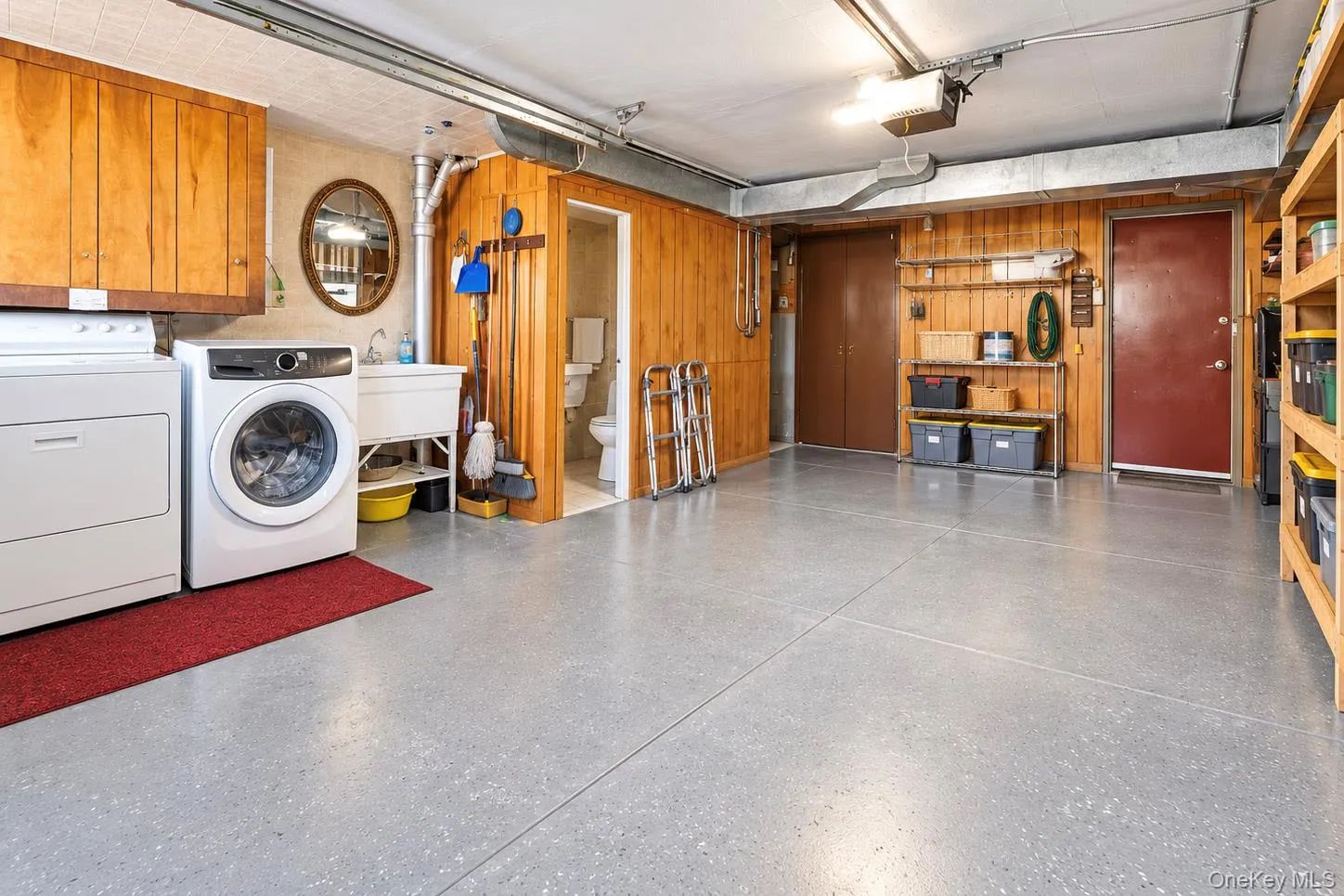 Expansive garage space with durable flooring, wood paneling, built-in shelving, and a utility sink Expansive garage space with durable flooring, wood paneling, built-in shelving, and a utility sink