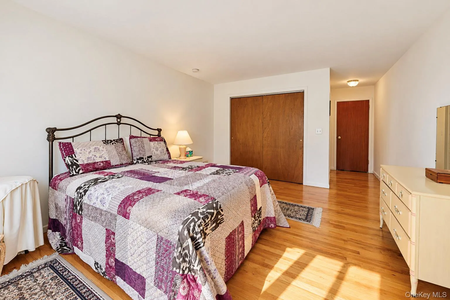 Hardwood flooring throughout, offering a built-in closet with wood-finish doors and a recessed ceiling light in the hallway Hardwood flooring throughout, offering a built-in closet with wood-finish doors and a recessed ceiling light in the hallway