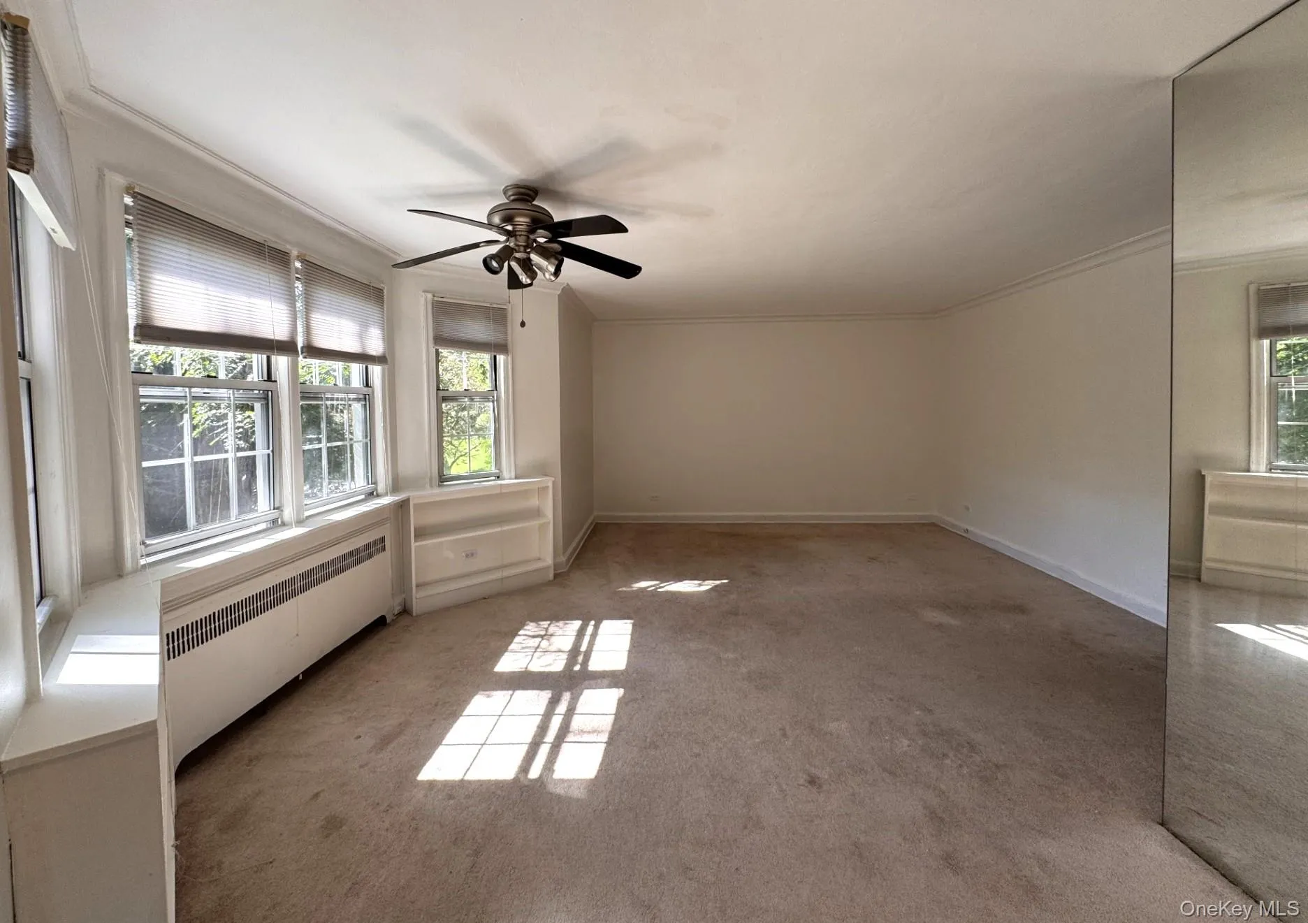 Multiple windows with blinds, ceiling fan with integrated lighting, built-in shelving. Multiple windows with blinds, ceiling fan with integrated lighting, built-in shelving.
