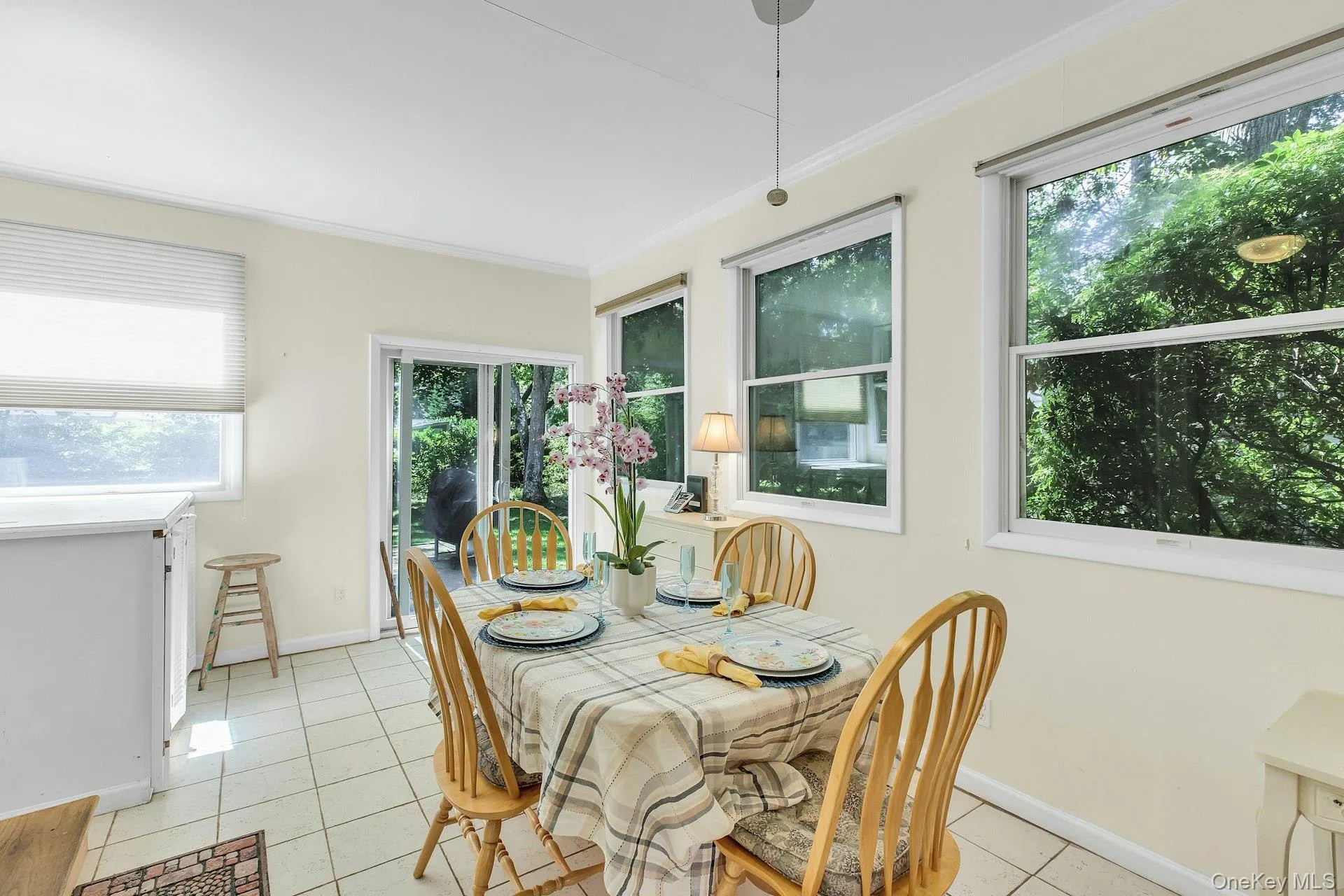 Tile flooring, multiple windows, sliding glass door, crown molding, and a pendant light fixture Tile flooring, multiple windows, sliding glass door, crown molding, and a pendant light fixture