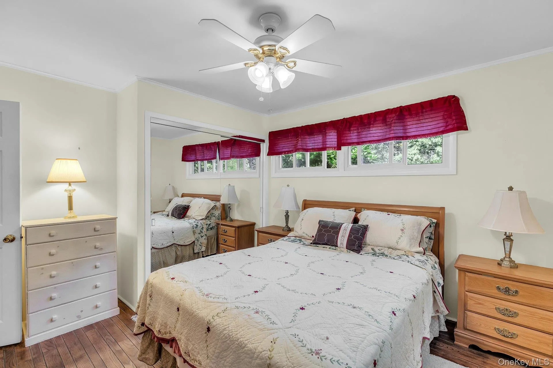 Hardwood flooring, ceiling fan with integrated lighting, built-in mirrored closet, and a horizontal window Hardwood flooring, ceiling fan with integrated lighting, built-in mirrored closet, and a horizontal window