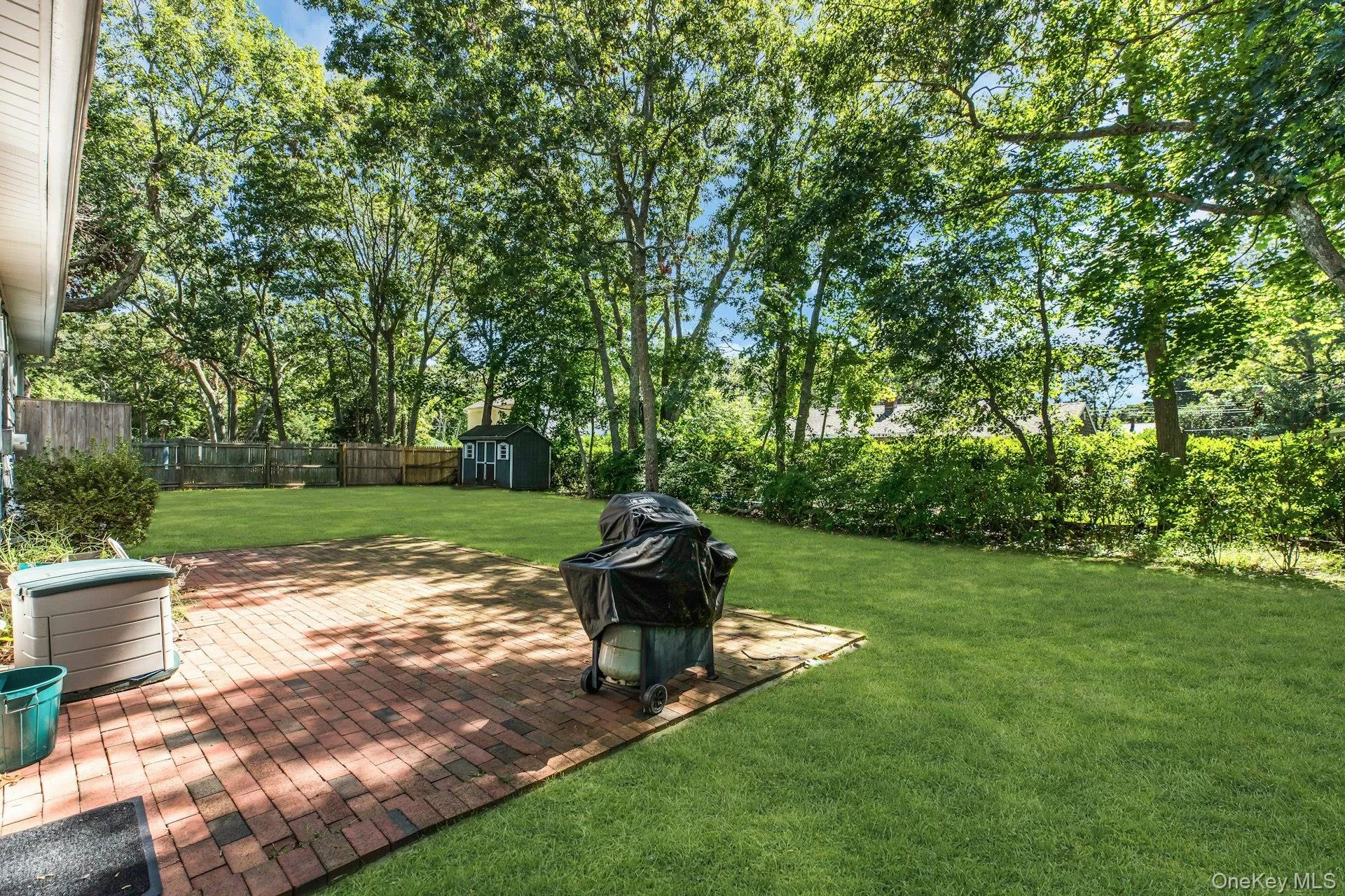 Expansive green lawn with mature trees and a brick paver patio Expansive green lawn with mature trees and a brick paver patio