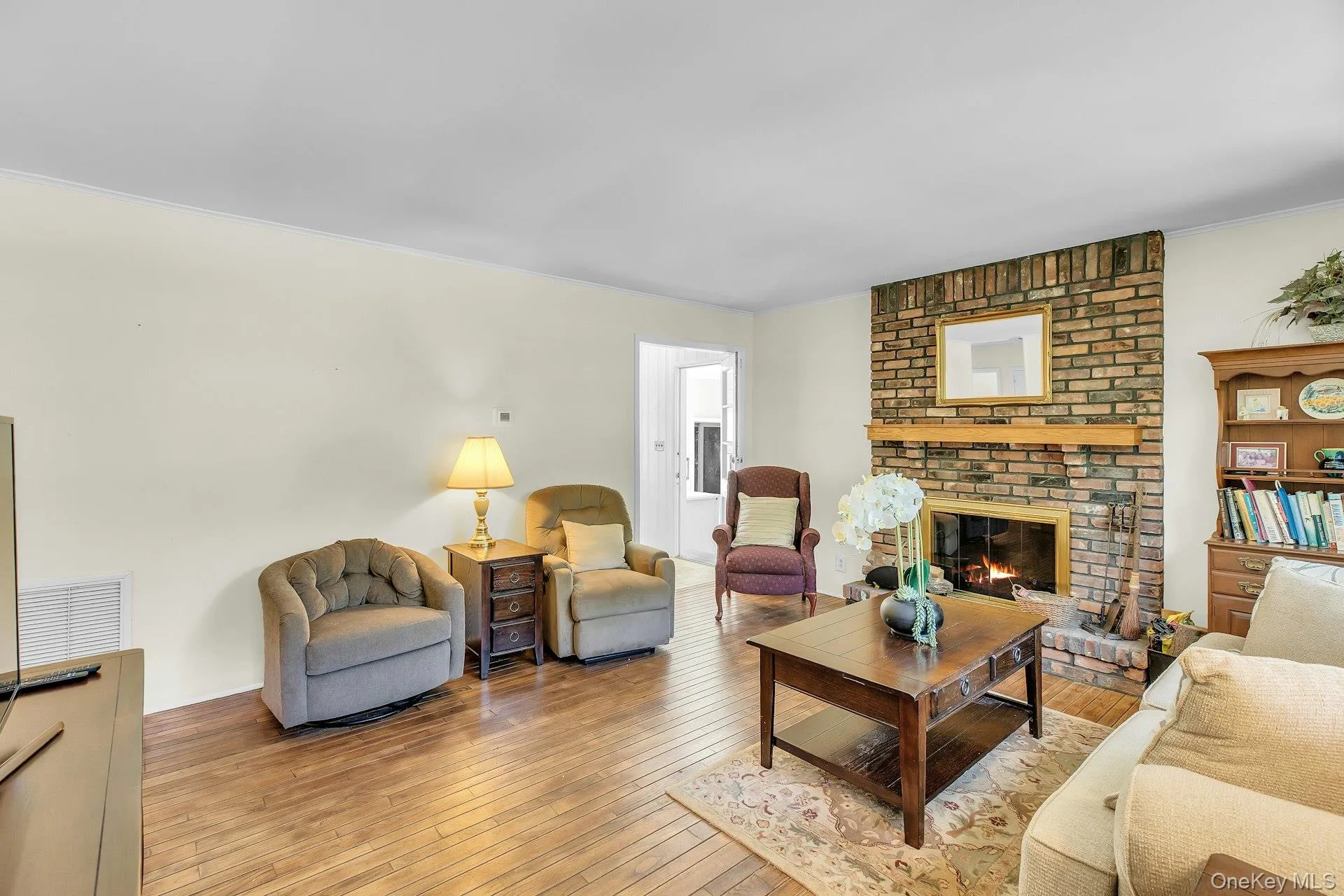 Brick fireplace with a wood mantle, wood-finish flooring, and crown molding Brick fireplace with a wood mantle, wood-finish flooring, and crown molding