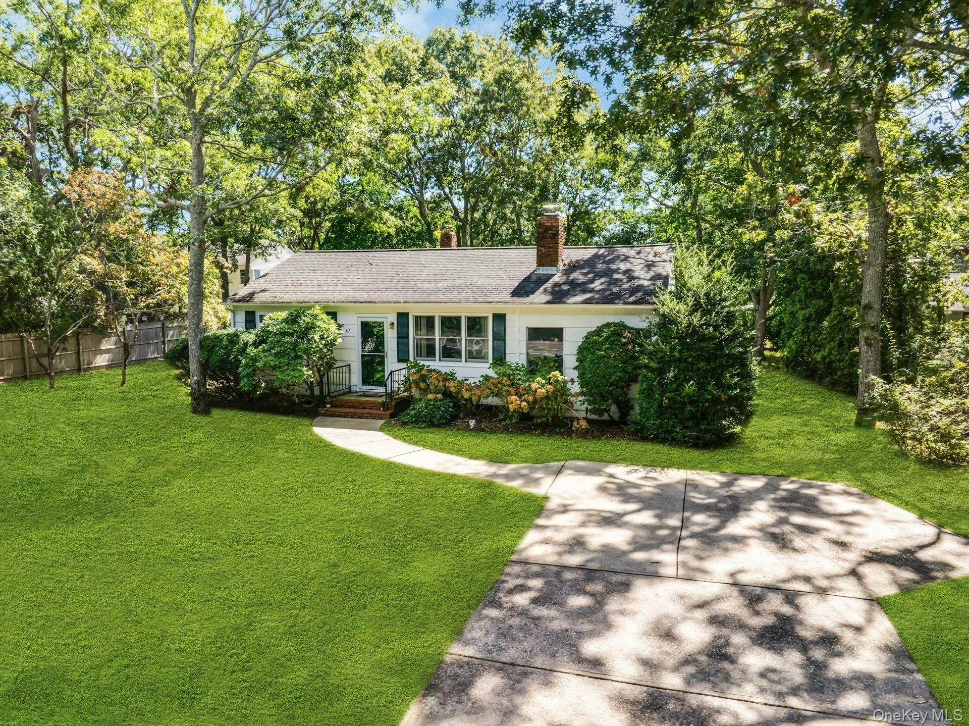 Ranch-style residence featuring white siding, green window shutters, and mature trees Ranch-style residence featuring white siding, green window shutters, and mature trees