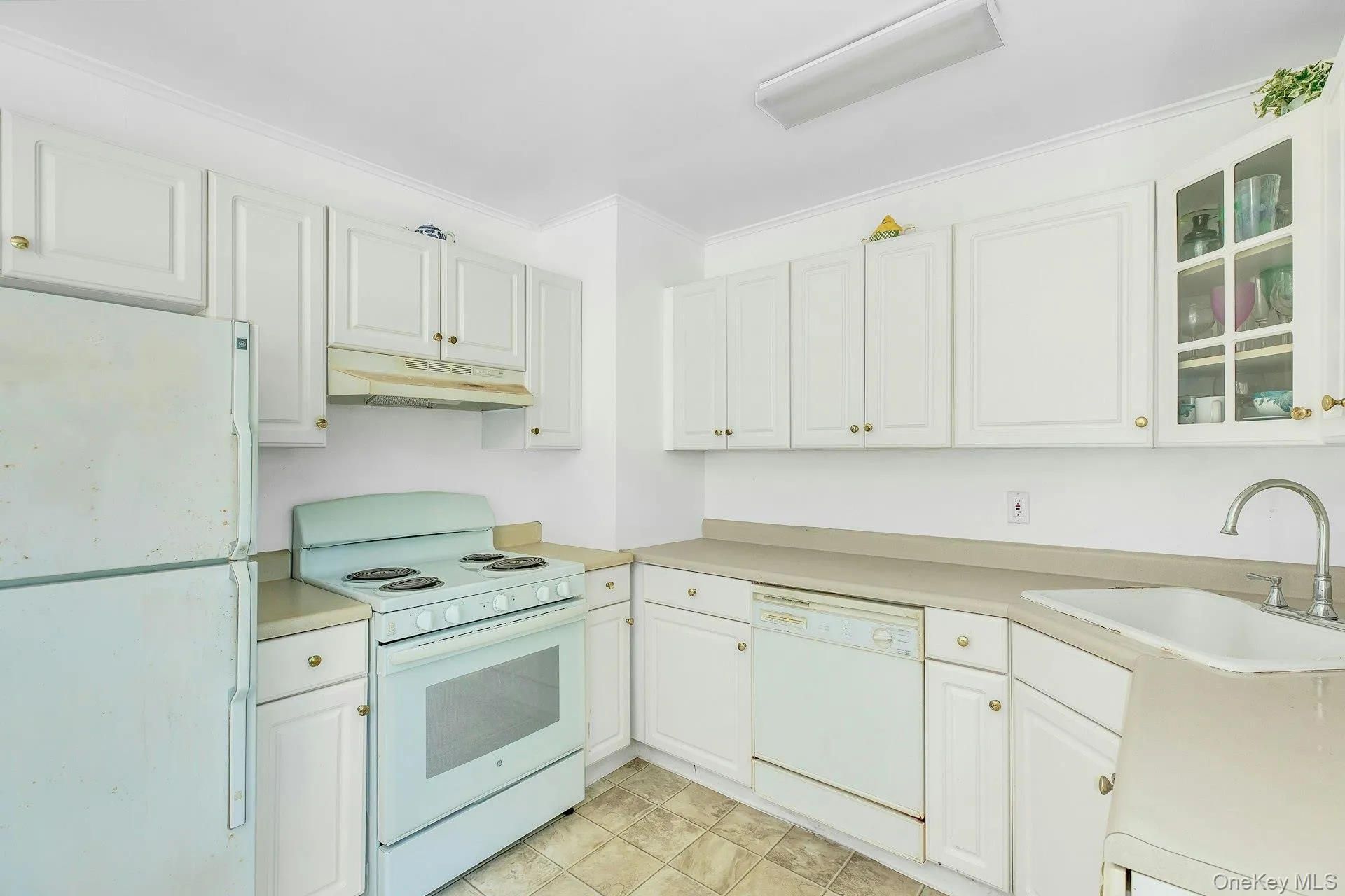 Kitchen featuring white cabinetry, light-toned countertops, tile flooring, a white range, and a white refrigerator Kitchen featuring white cabinetry, light-toned countertops, tile flooring, a white range, and a white refrigerator