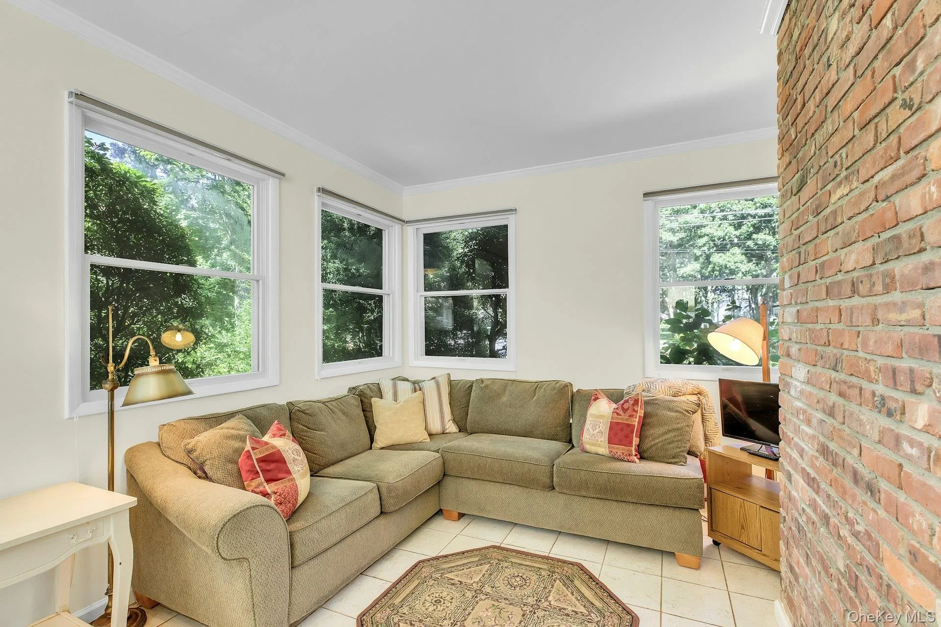 Exposed brick accent wall, multiple windows, crown molding, and tiled flooring Exposed brick accent wall, multiple windows, crown molding, and tiled flooring