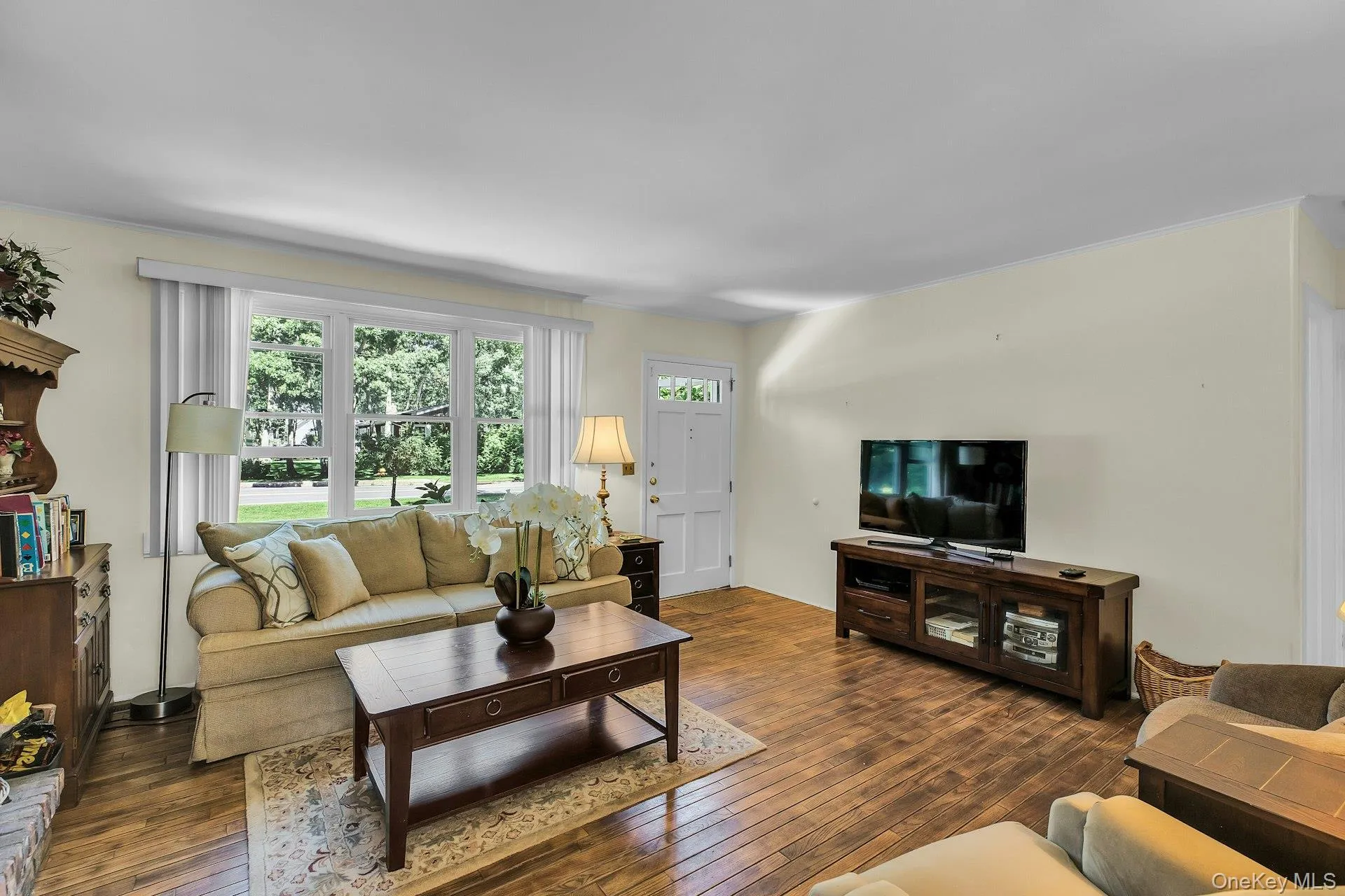 Light-toned wall finishes, wide plank wood-finish flooring, and a multi-pane window Light-toned wall finishes, wide plank wood-finish flooring, and a multi-pane window