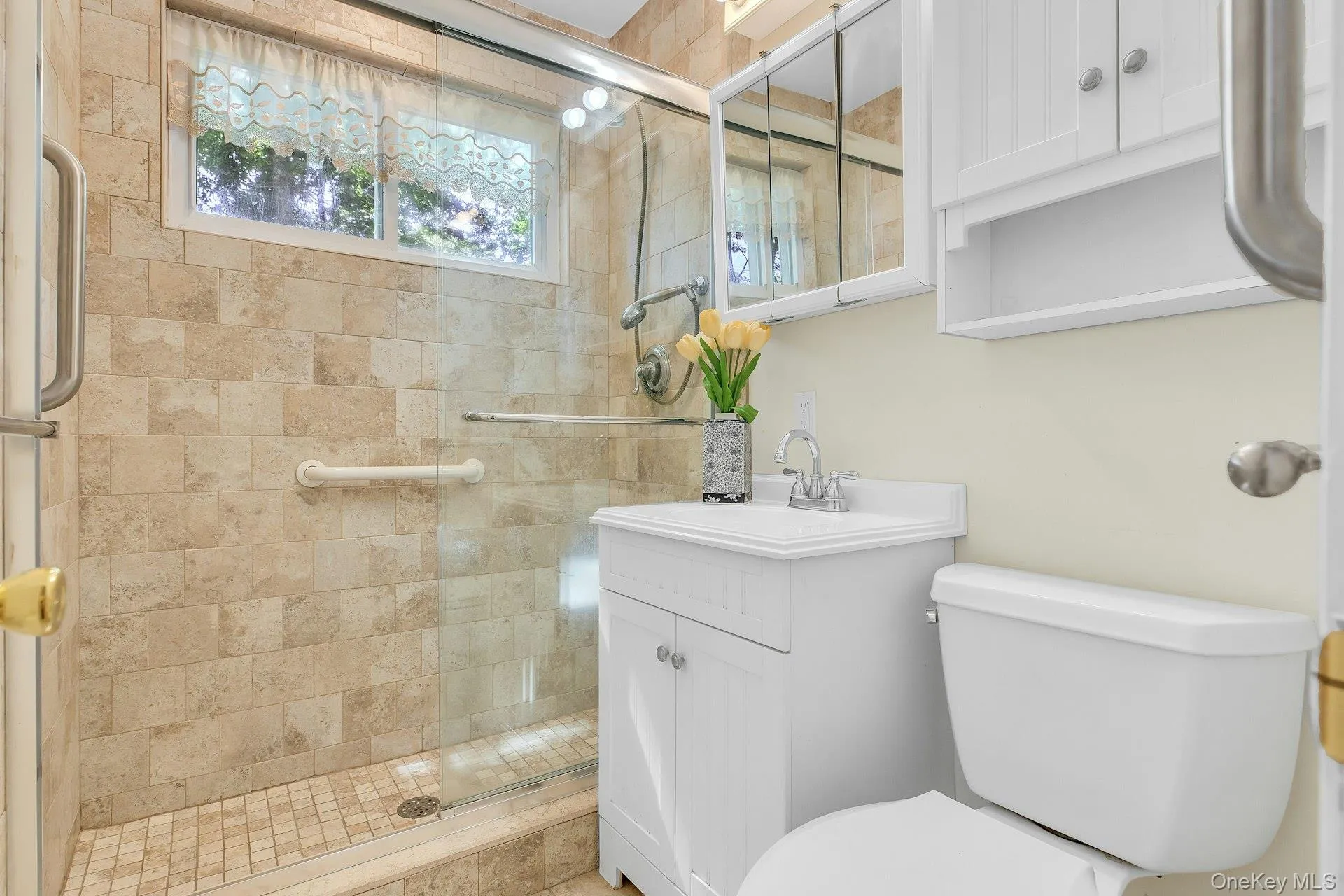 Glass-enclosed shower with full-height tile surround, window, and grab bars Glass-enclosed shower with full-height tile surround, window, and grab bars