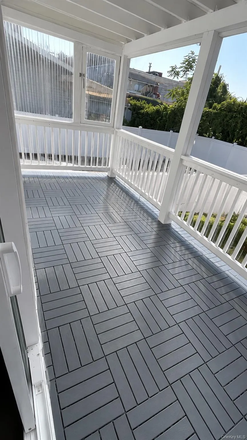 Enclosed patio featuring white railings, patterned gray flooring, and a white ceiling Enclosed patio featuring white railings, patterned gray flooring, and a white ceiling