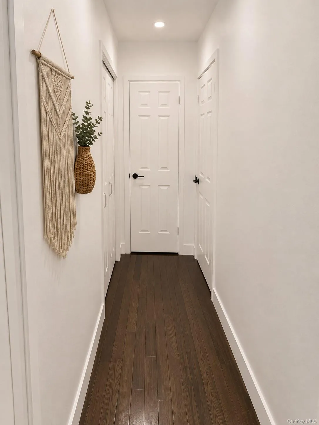 Dark wood-finish flooring with white baseboards, white walls, and recessed lighting Dark wood-finish flooring with white baseboards, white walls, and recessed lighting
