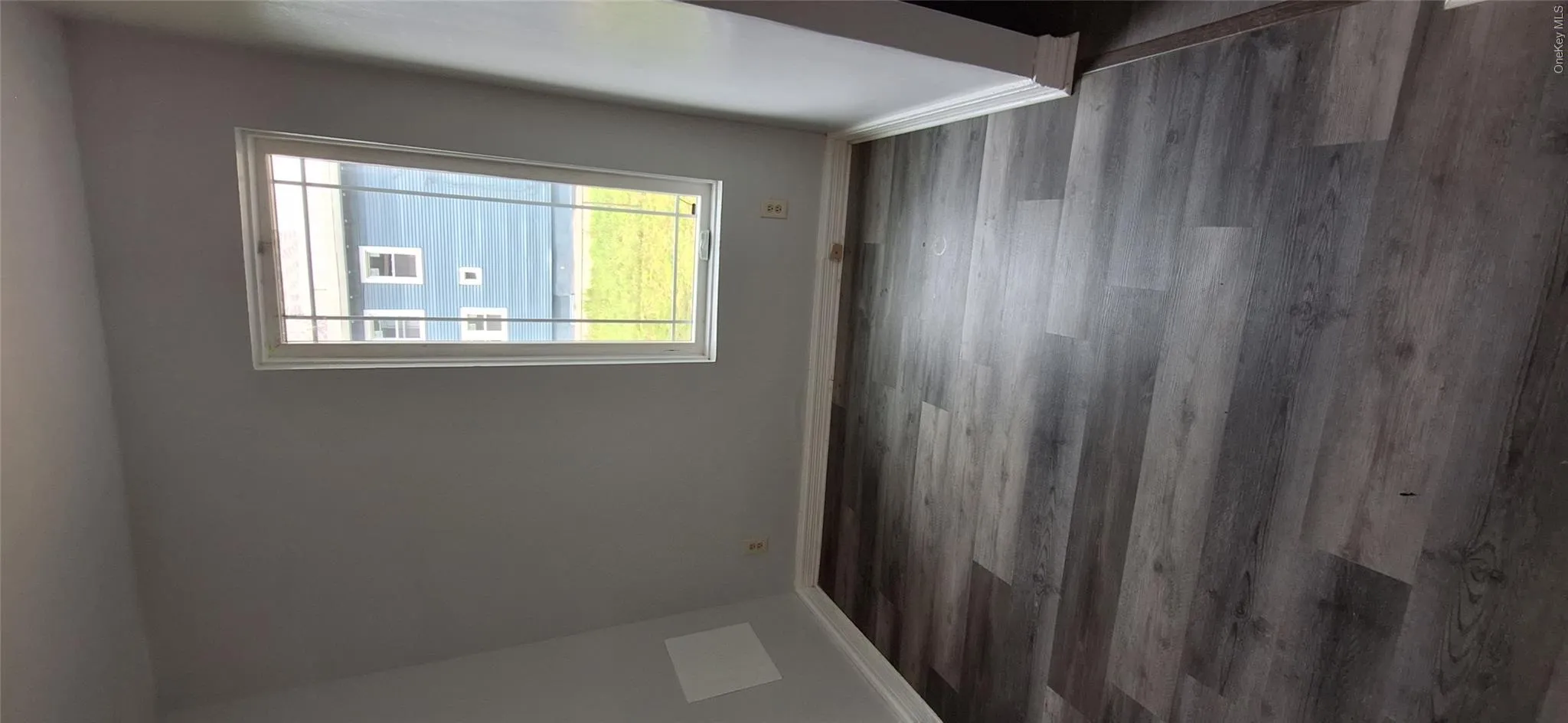 Bedroom featuring contemporary gray laminate flooring and baseboards Bedroom featuring contemporary gray laminate flooring and baseboards