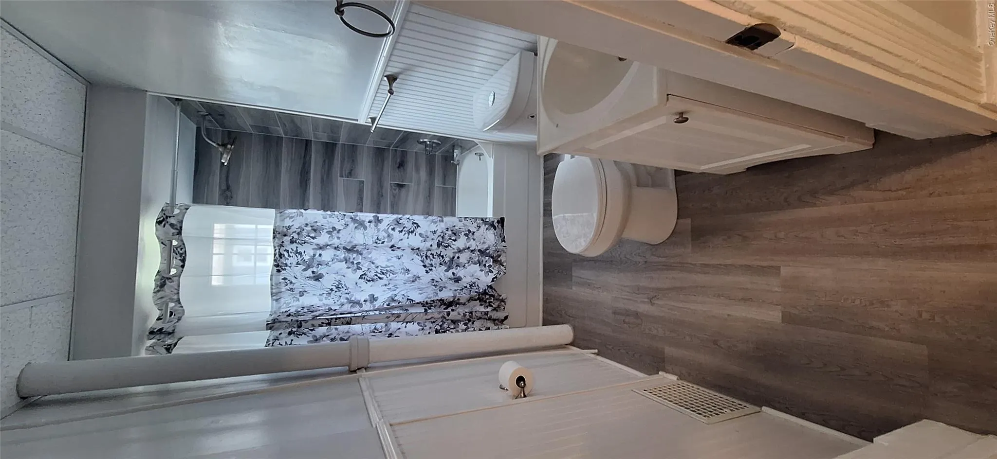 Full bath with visible vents, shower / bathing tub combination, toilet, vanity, and wood finished floors Full bath with visible vents, shower / bathing tub combination, toilet, vanity, and wood finished floors