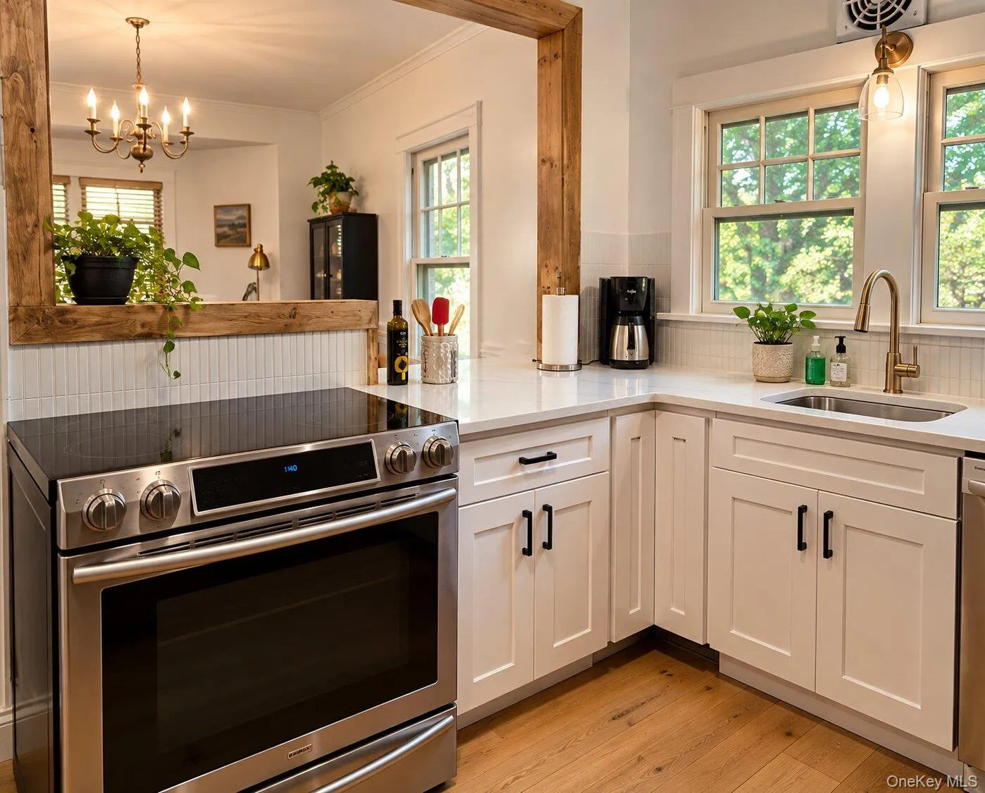 Virtually Staged. Kitchen with stainless steel range with electric stovetop, a notable chandelier, white cabinets, and light stone countertops Virtually Staged. Kitchen with stainless steel range with electric stovetop, a notable chandelier, white cabinets, and light stone countertops