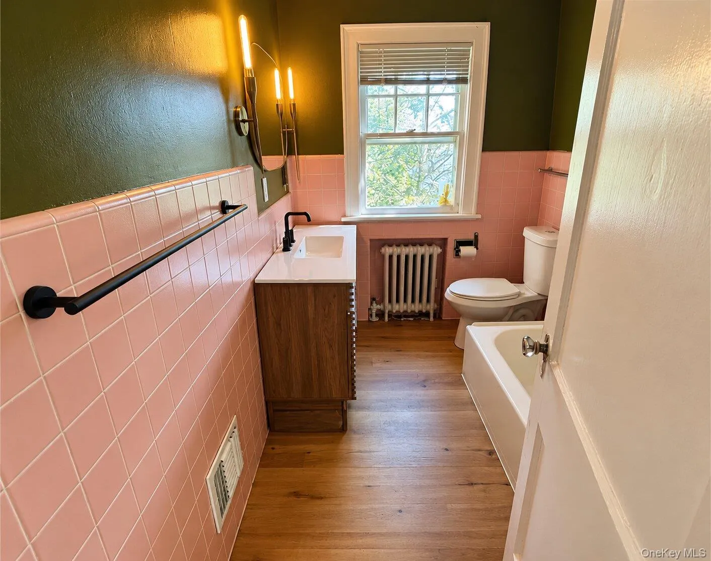 Bathroom with radiator heating unit, toilet, tile walls, a bathing tub, and vanity Bathroom with radiator heating unit, toilet, tile walls, a bathing tub, and vanity