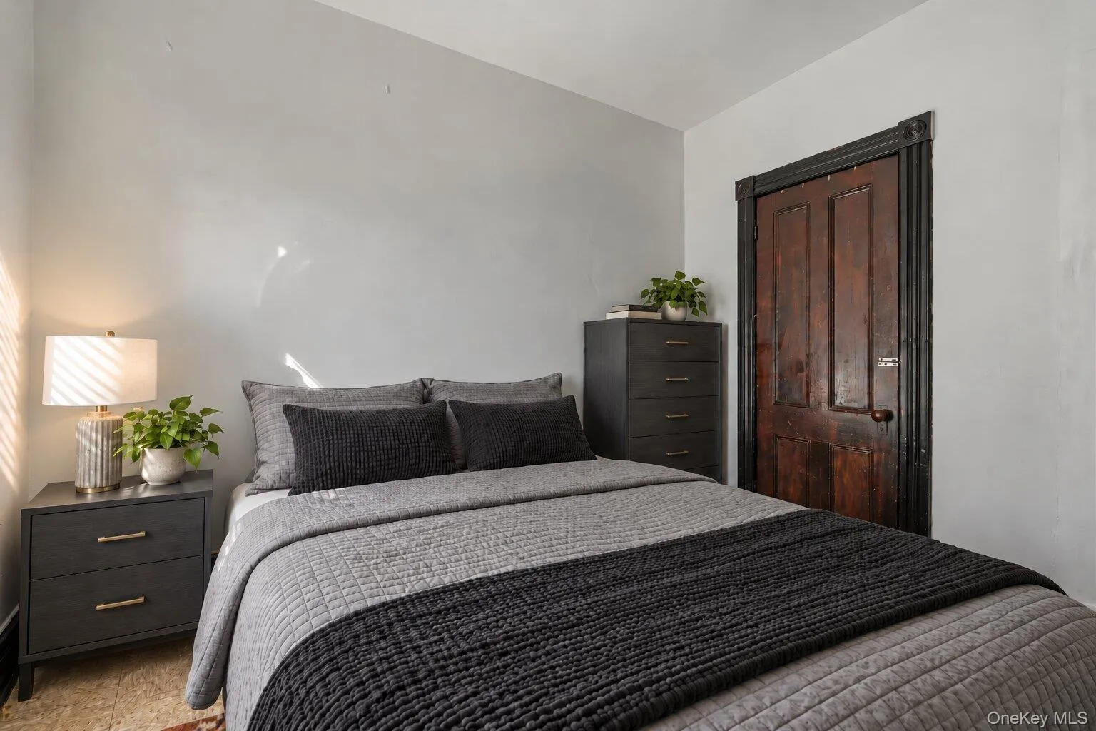 Virtually Staged Furniture. Alternate view of the bedroom featuring original wood door and trim with a simple neutral interior. Virtually Staged Furniture. Alternate view of the bedroom featuring original wood door and trim with a simple neutral interior.
