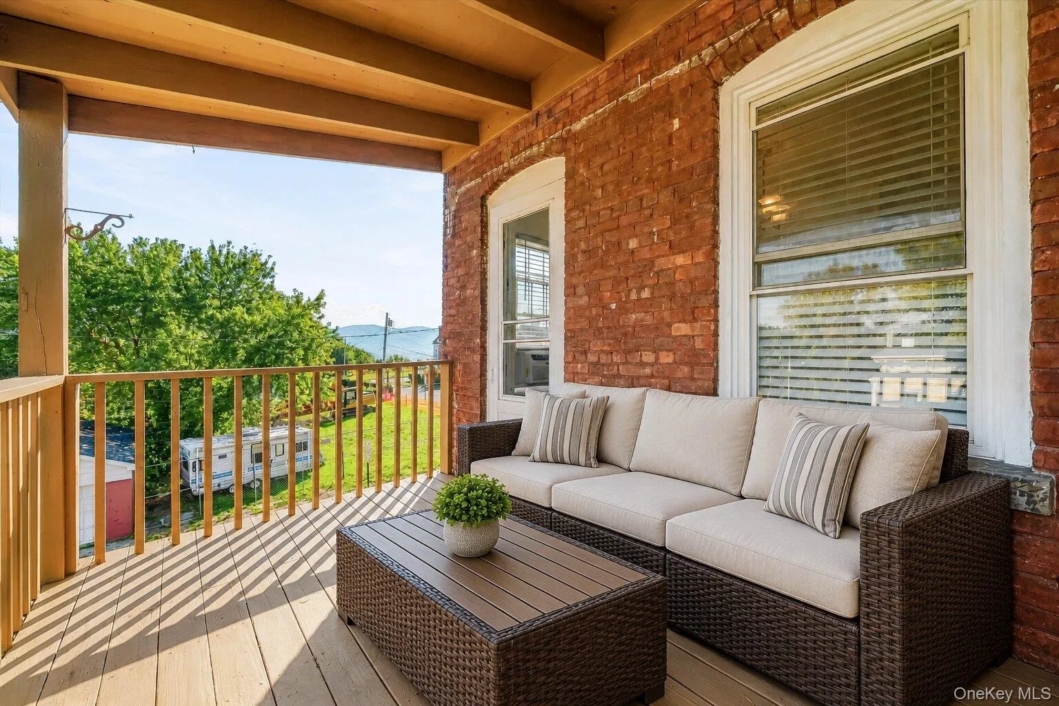 Virtually Staged Furniture. Covered porch with exposed brick exterior wall, wood railing, and elevated neighborhood views. Virtually Staged Furniture. Covered porch with exposed brick exterior wall, wood railing, and elevated neighborhood views.