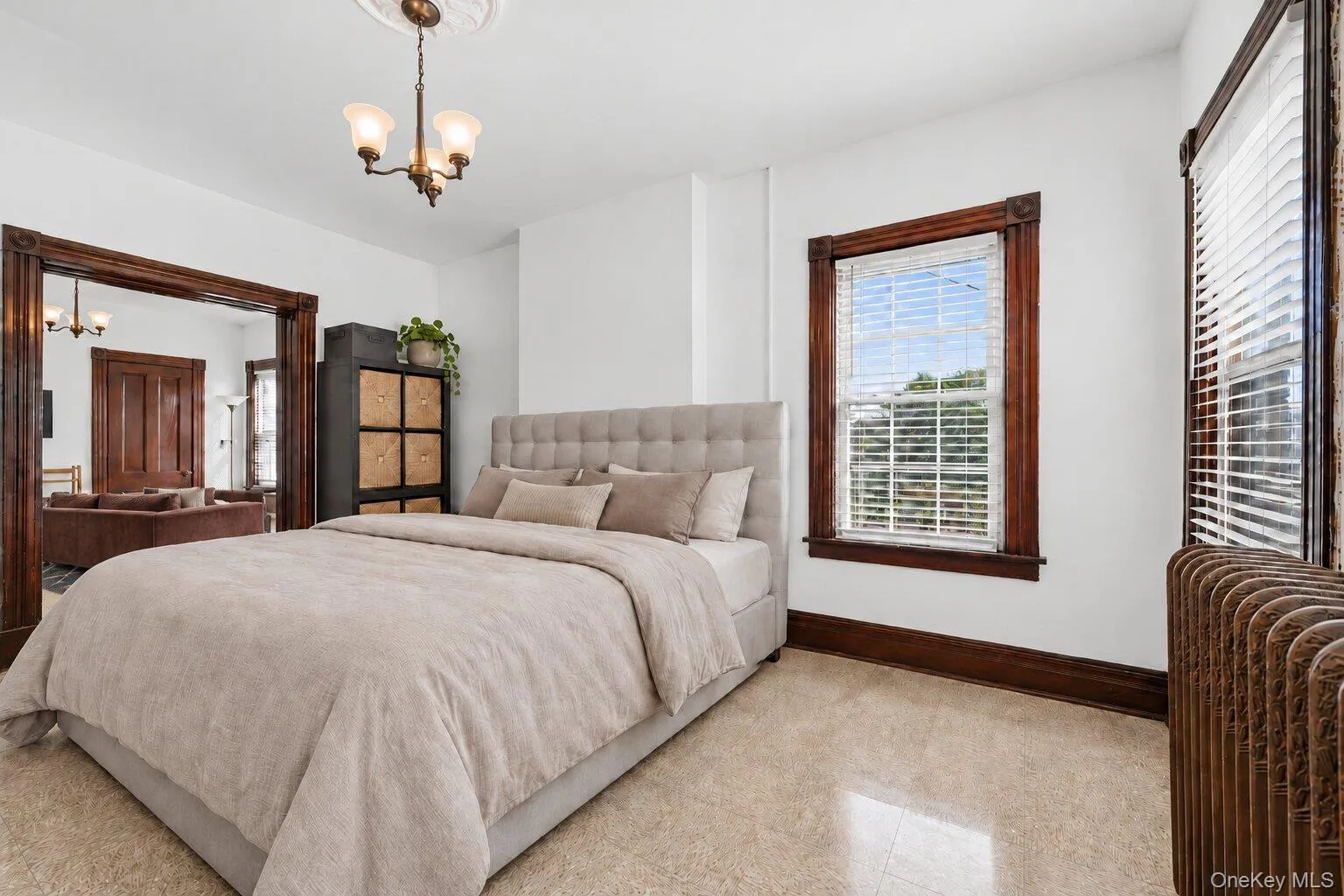 Virtually Staged Furniture. Bedroom with multiple windows, original dark wood trim, radiator, and generous natural light. Virtually Staged Furniture. Bedroom with multiple windows, original dark wood trim, radiator, and generous natural light.