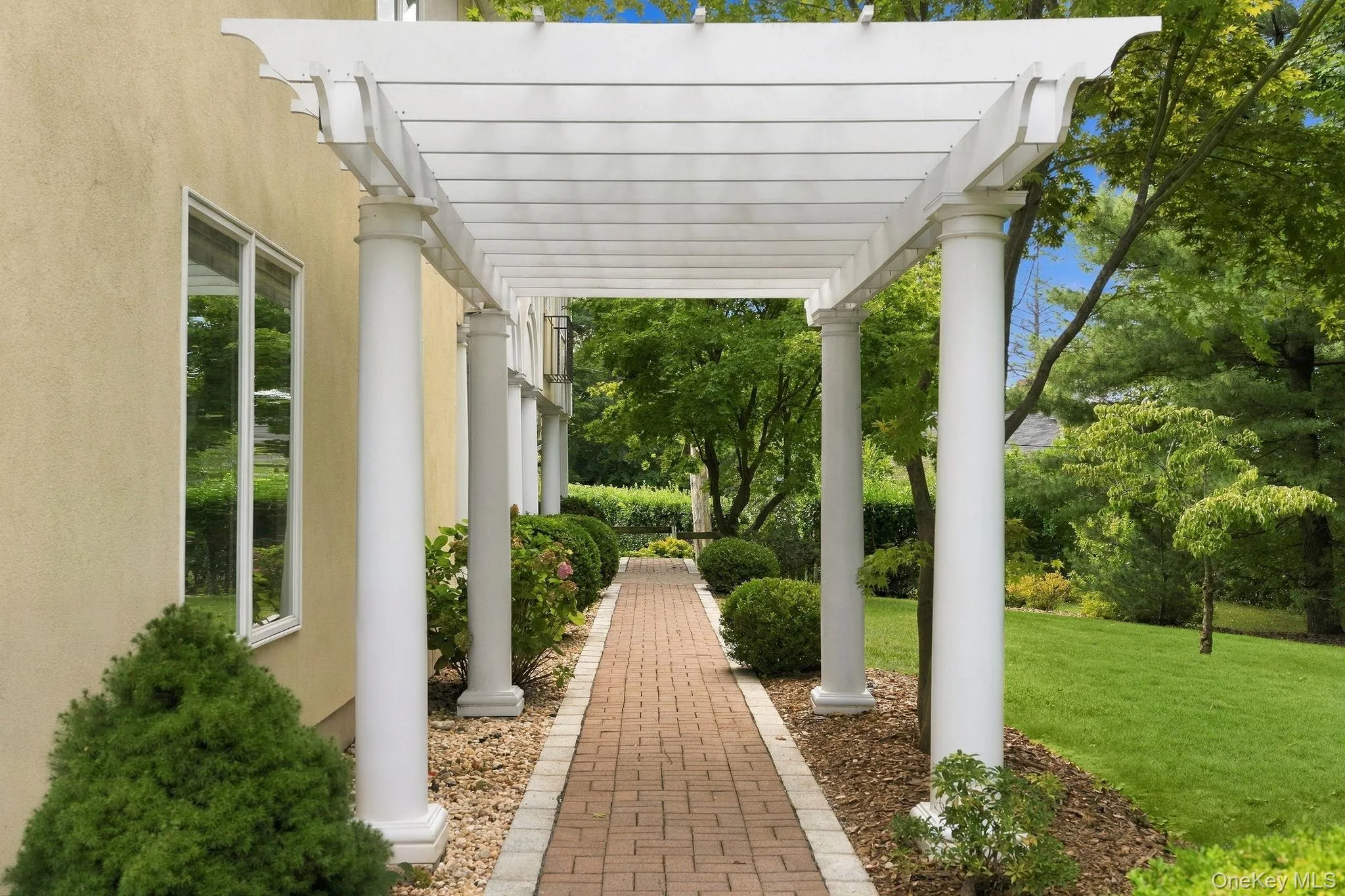 A gracious garden walkway leads beneath an impressive columned portico. A gracious garden walkway leads beneath an impressive columned portico.