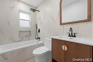 Bathtub with marble-look tile surround, black rainfall showerhead, and recessed niche Bathtub with marble-look tile surround, black rainfall showerhead, and recessed niche