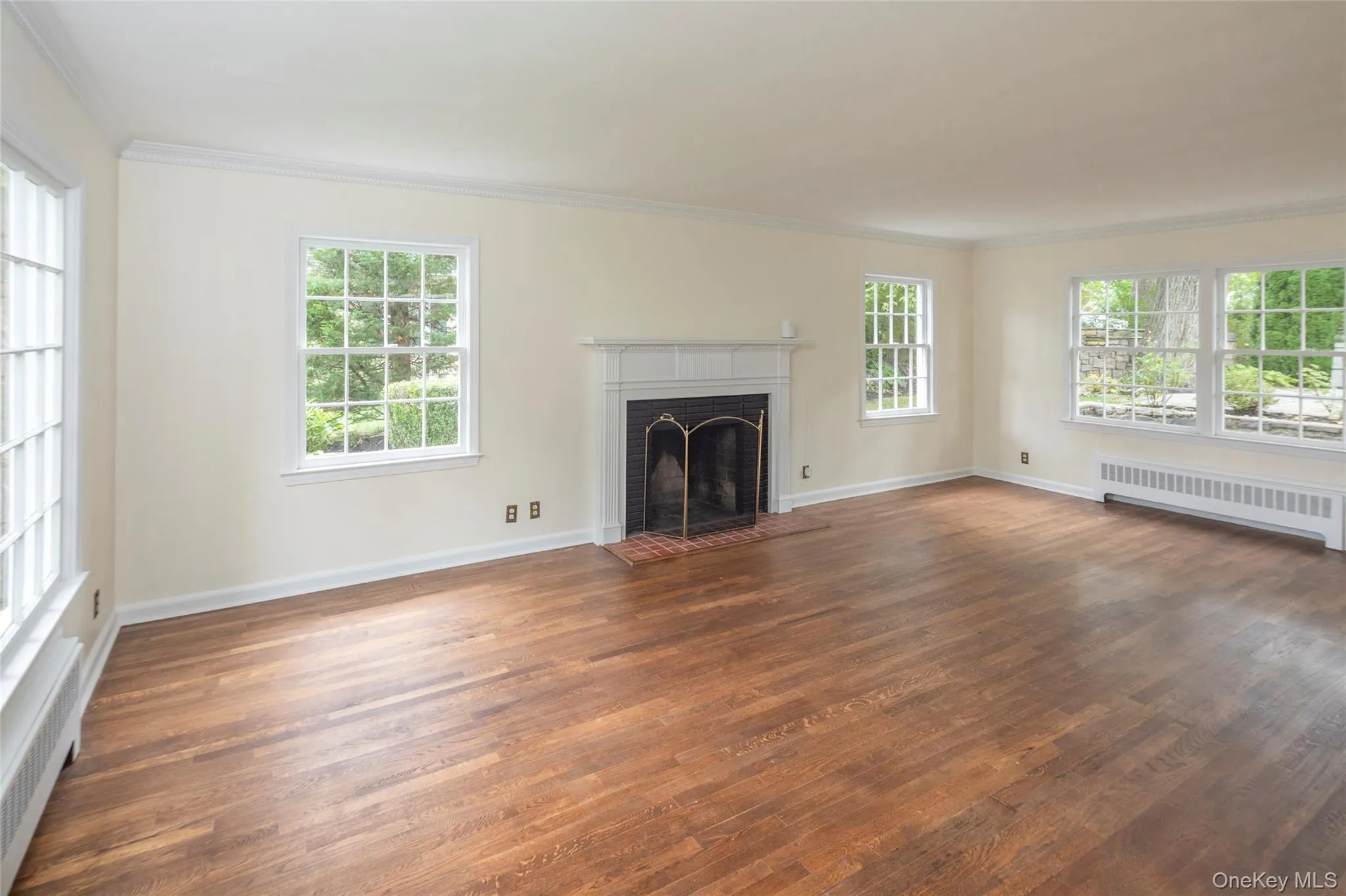 Spacious living room has wood burning fireplace and large windows on three sides. Spacious living room has wood burning fireplace and large windows on three sides.