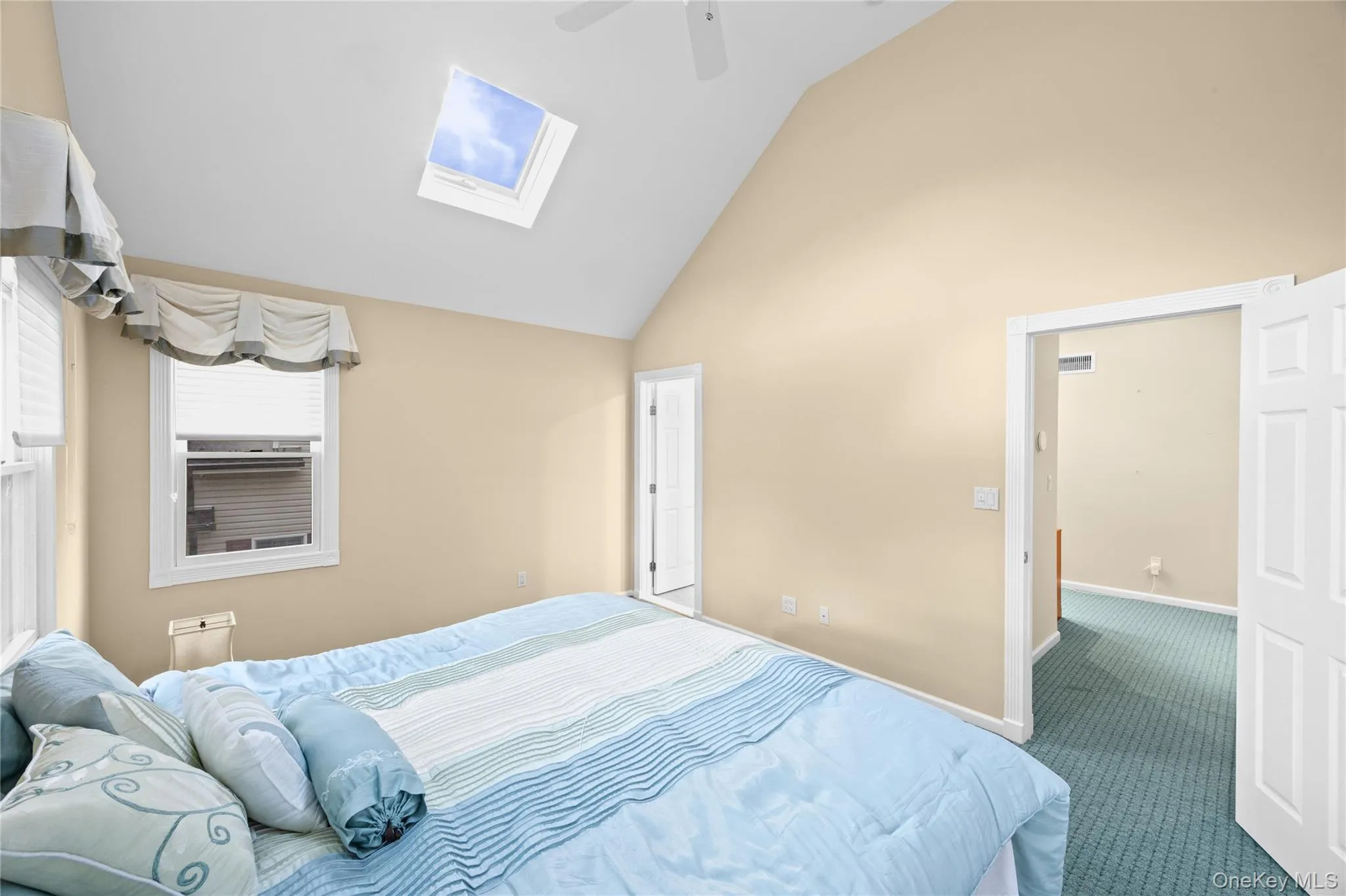 Vaulted ceiling, skylight, wall-mounted ceiling fan, window with blinds, and paneled interior doors Vaulted ceiling, skylight, wall-mounted ceiling fan, window with blinds, and paneled interior doors