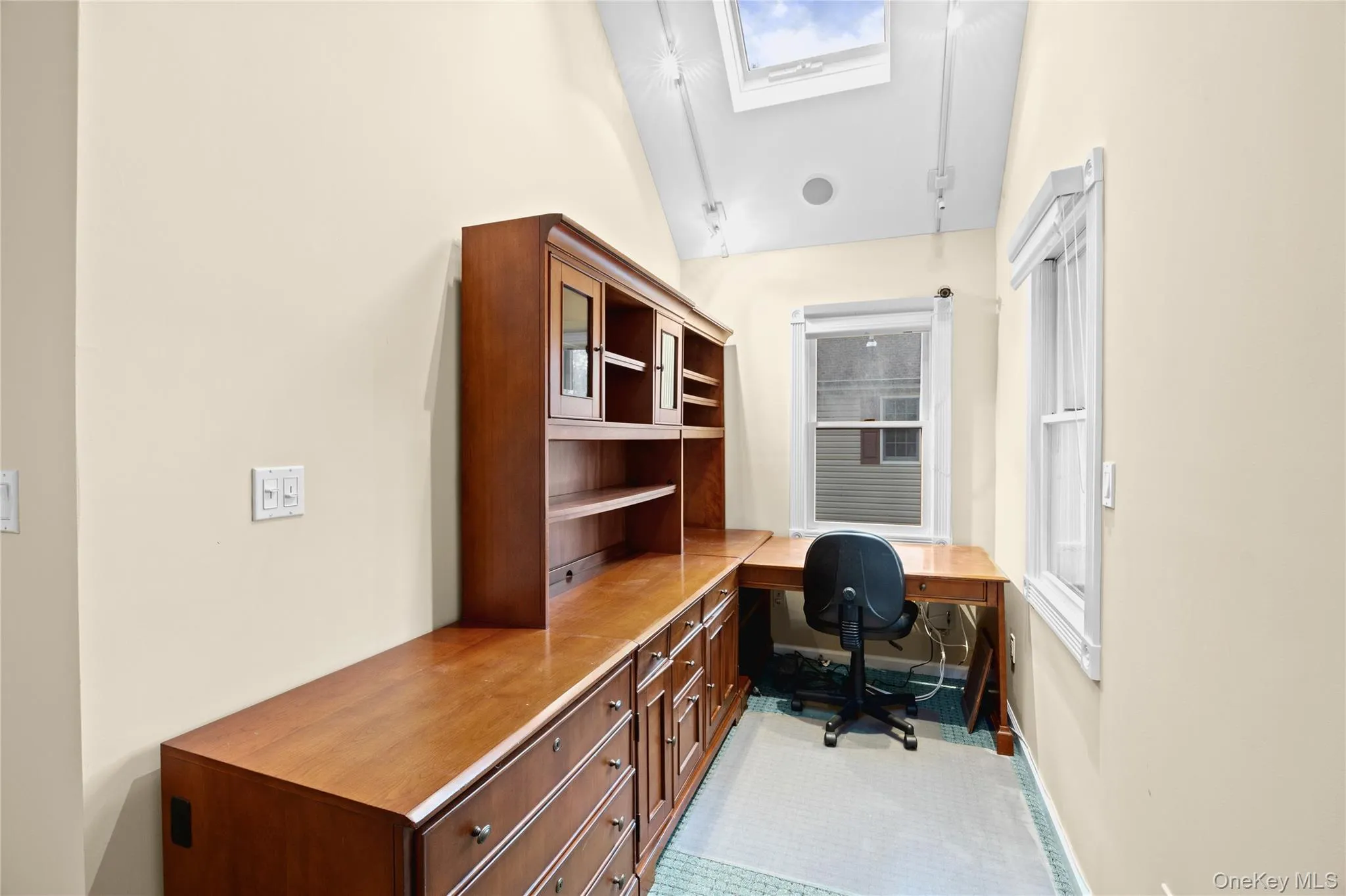 Built-in wood-finish desk with hutch and cabinetry, multiple windows, and a skylight Built-in wood-finish desk with hutch and cabinetry, multiple windows, and a skylight