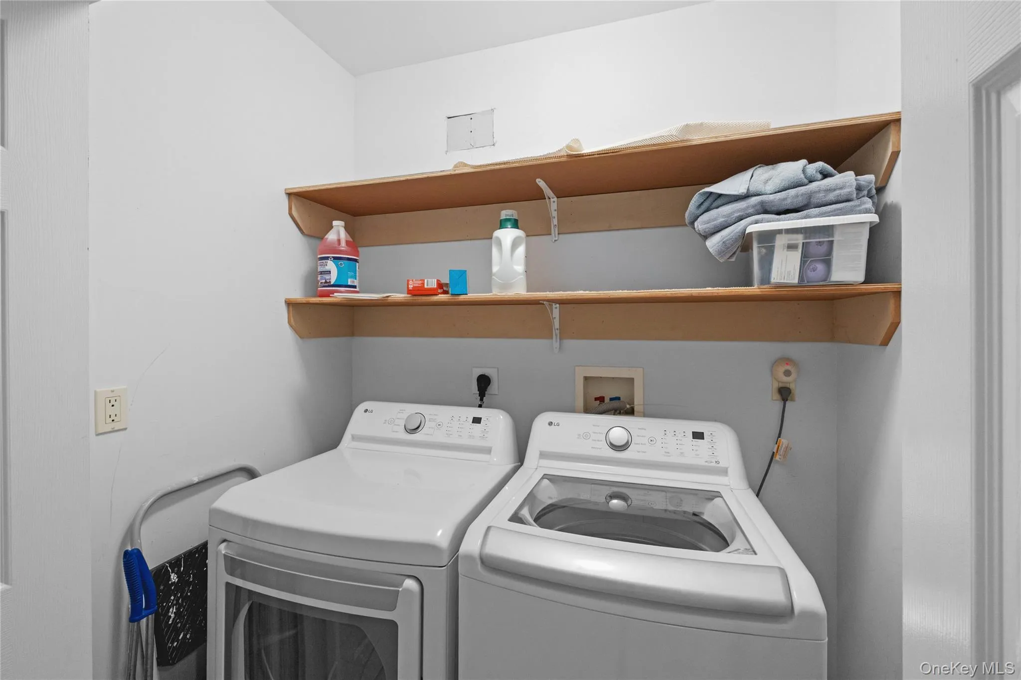 Laundry area featuring dual built-in shelves and white walls Laundry area featuring dual built-in shelves and white walls