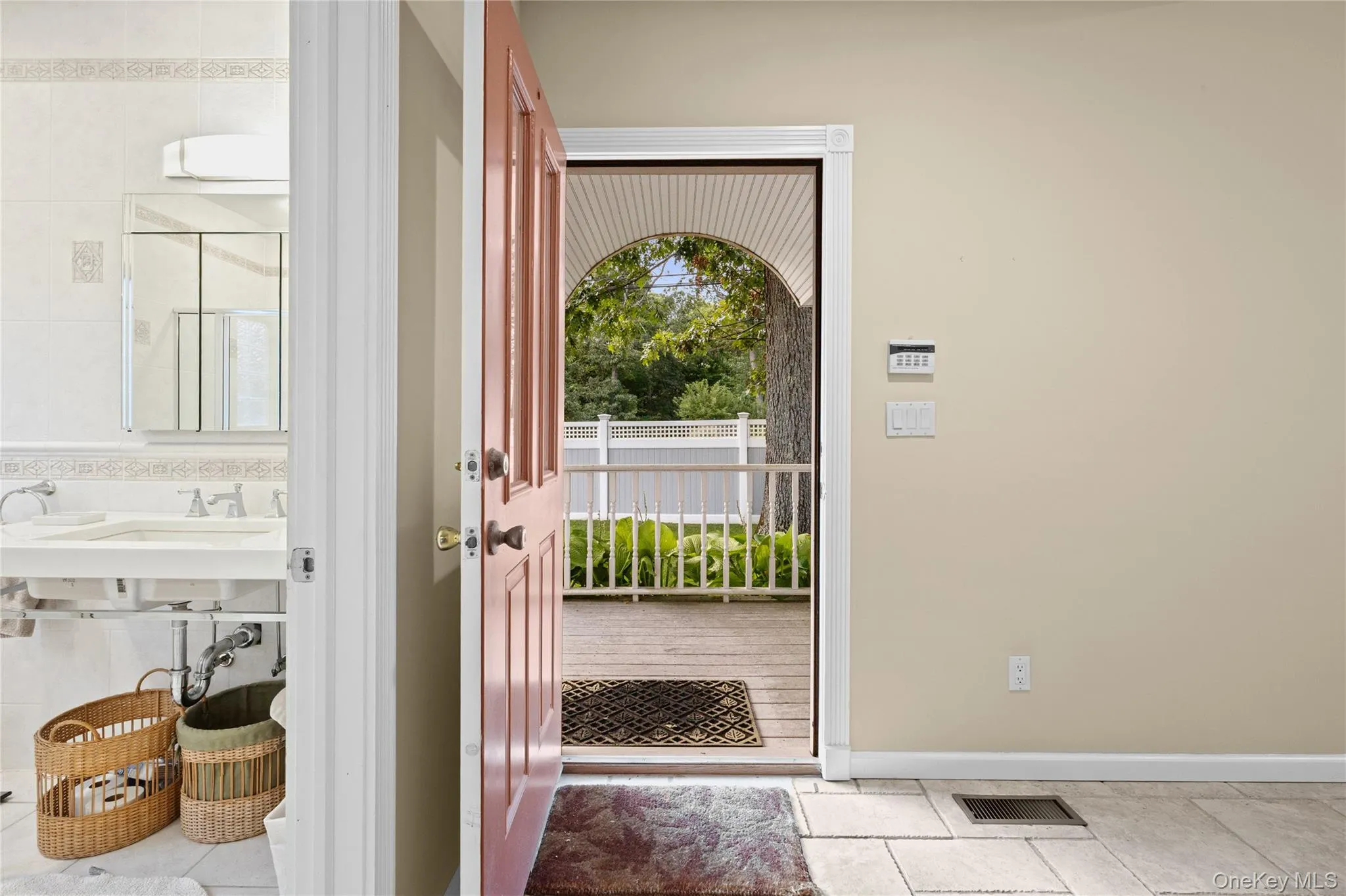 Tiled flooring, light-colored walls, white railing, and a wood deck Tiled flooring, light-colored walls, white railing, and a wood deck