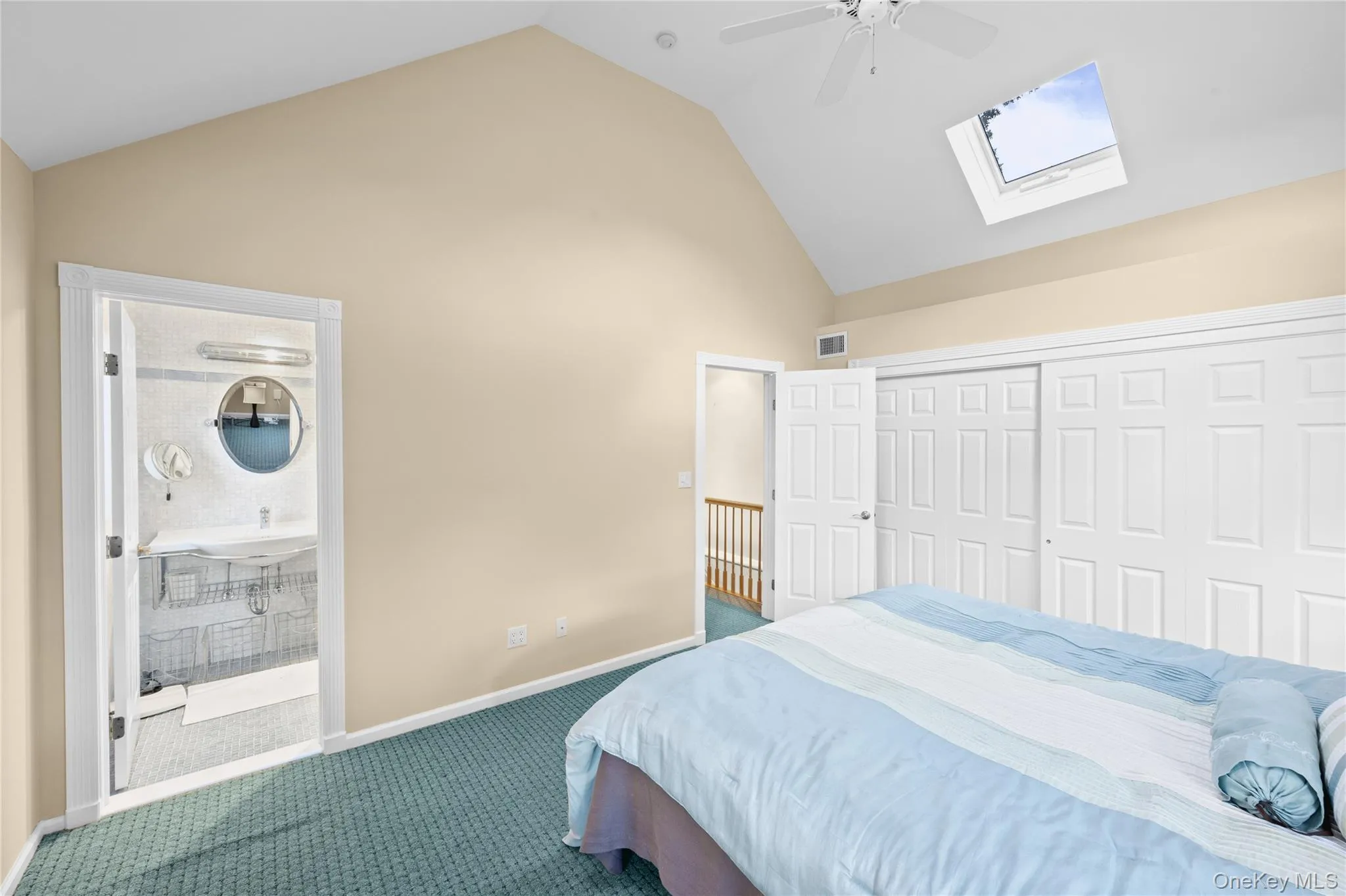 Vaulted ceiling with skylight and ceiling fan, neutral wall tones, and sliding closet doors Vaulted ceiling with skylight and ceiling fan, neutral wall tones, and sliding closet doors