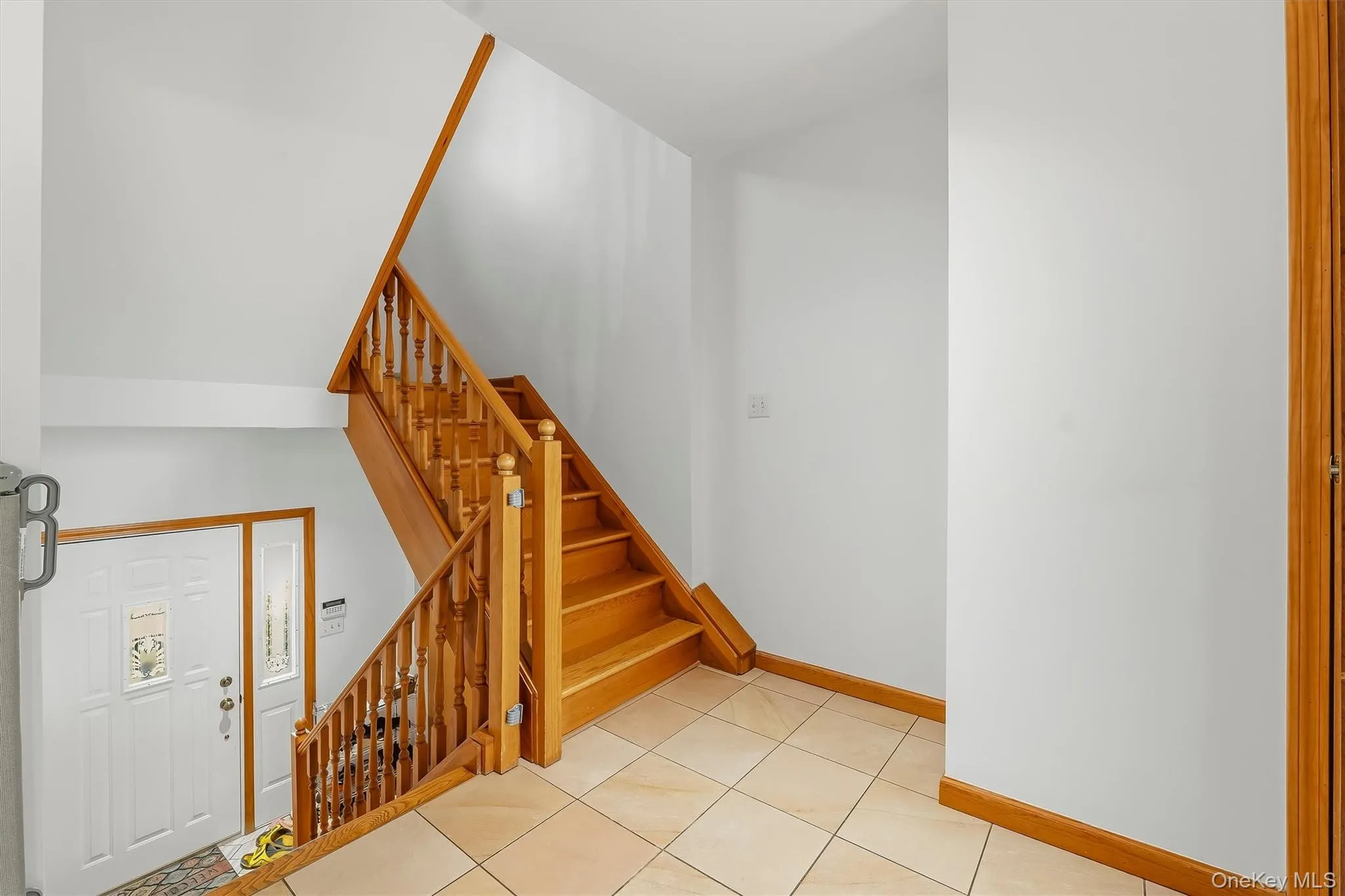 Hardwood staircase with turned balusters, tile flooring, and a white entry door with decorative glass inserts Hardwood staircase with turned balusters, tile flooring, and a white entry door with decorative glass inserts