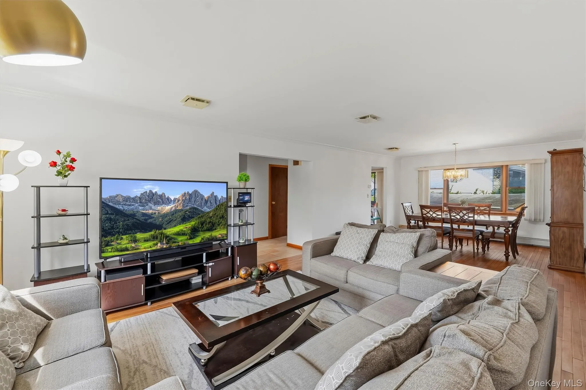 Open concept living area featuring wood-finish flooring, recessed lighting, and a dining space with a chandelier and large window Open concept living area featuring wood-finish flooring, recessed lighting, and a dining space with a chandelier and large window