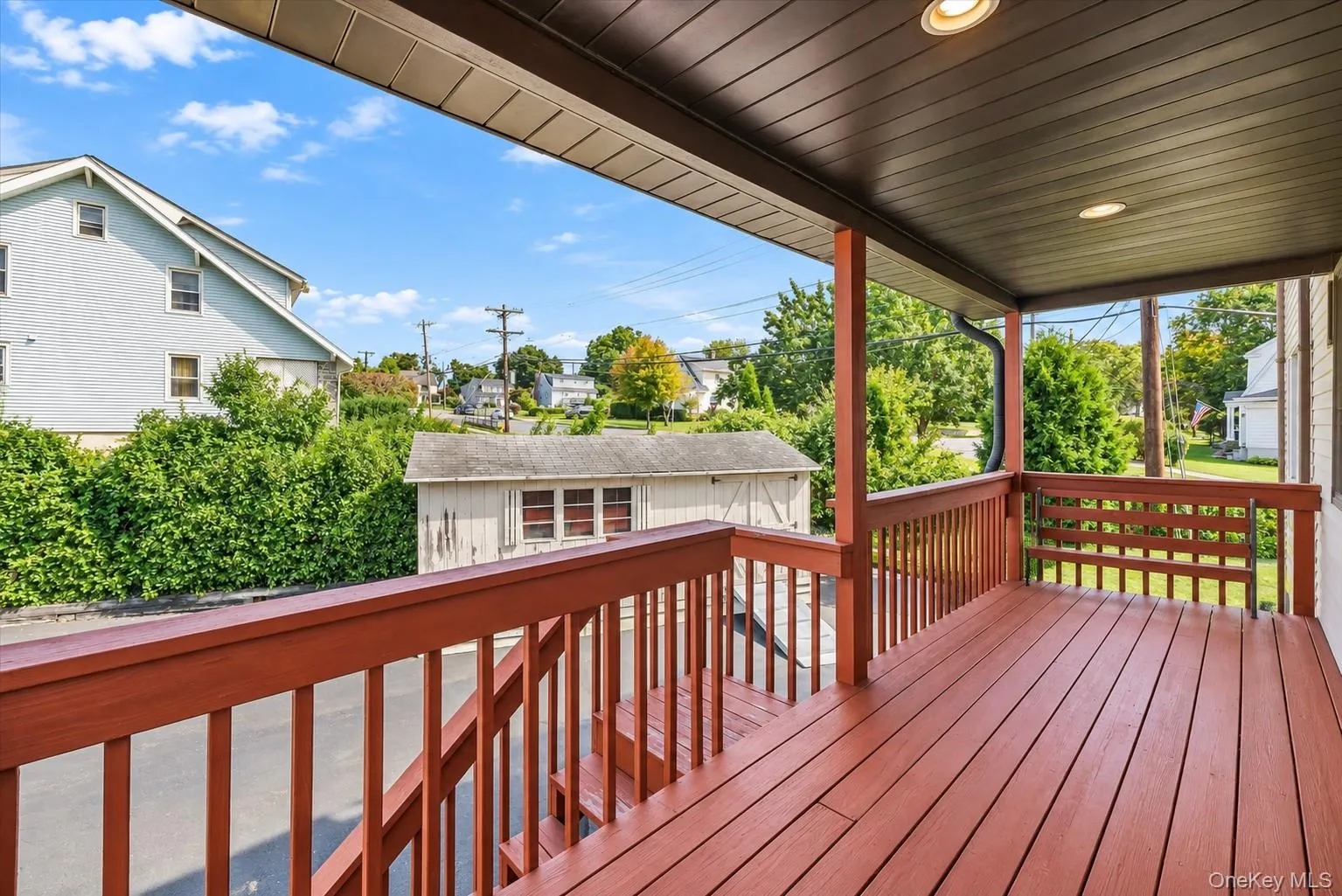 Covered porch with wood-finish decking, matching railing, and recessed lighting Covered porch with wood-finish decking, matching railing, and recessed lighting